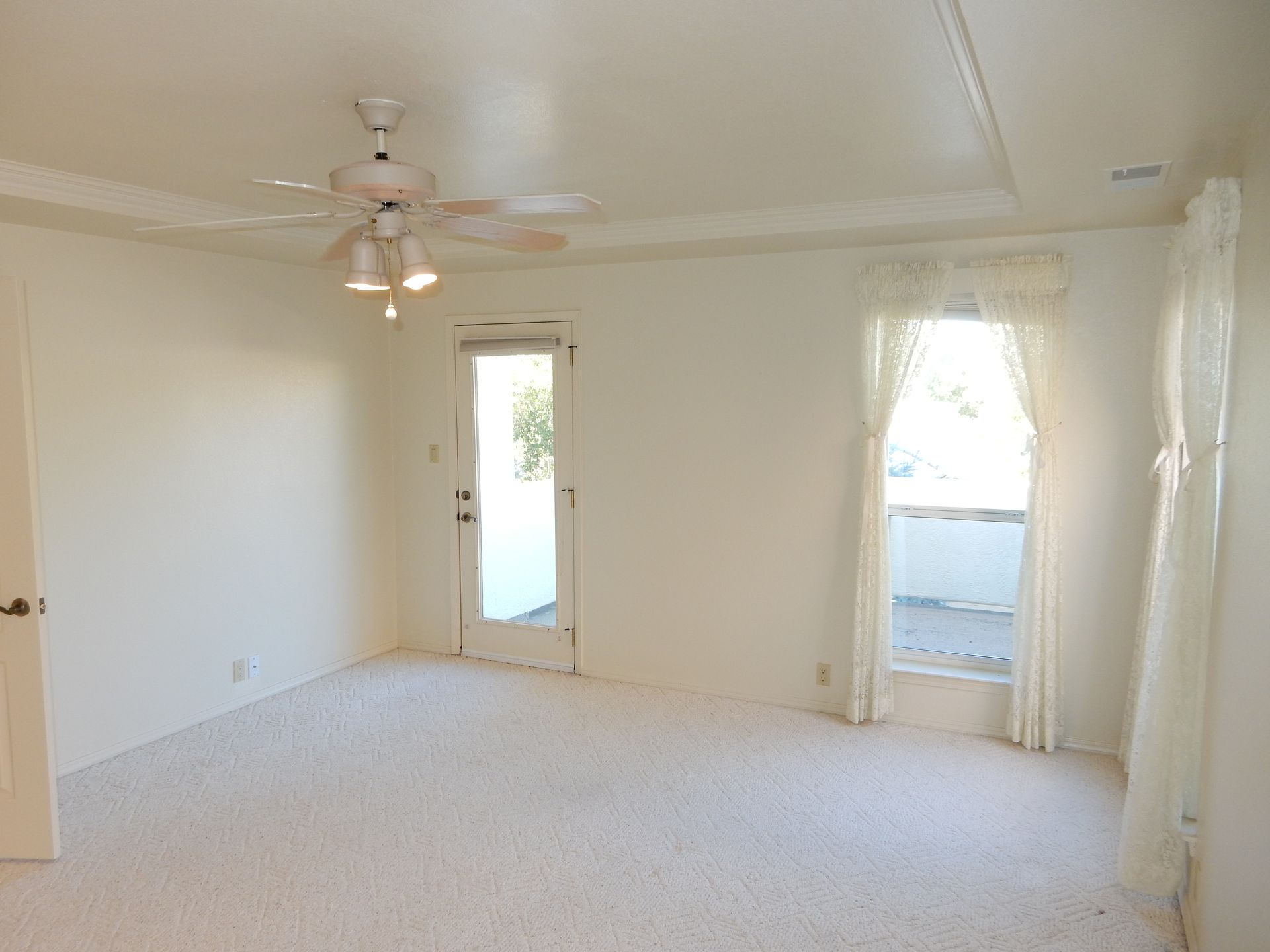 An empty room with a ceiling fan and a sliding glass door