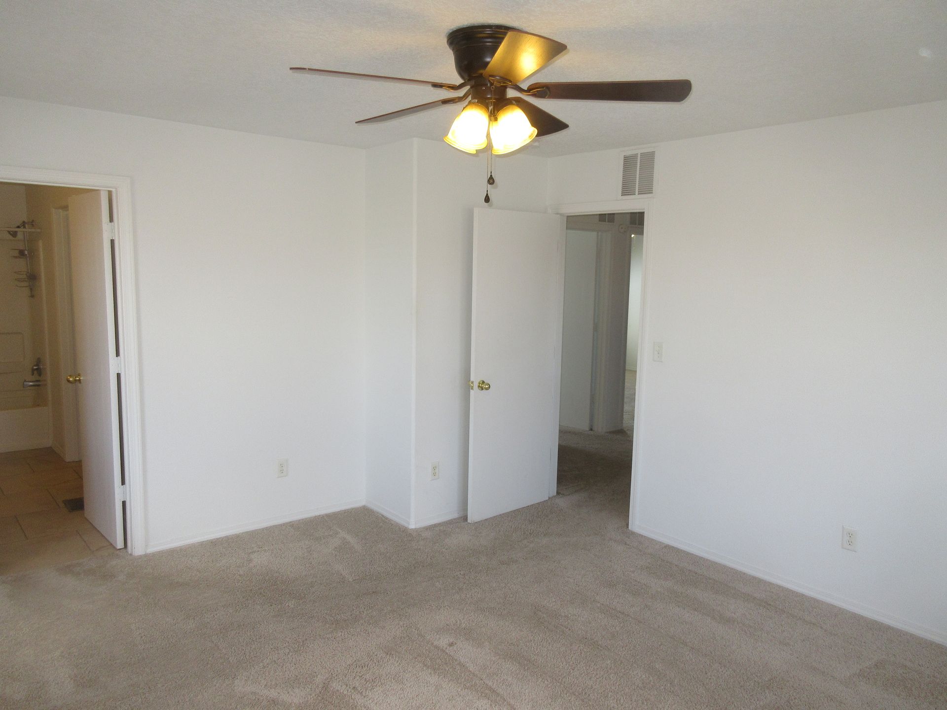 An empty bedroom with a ceiling fan and lights