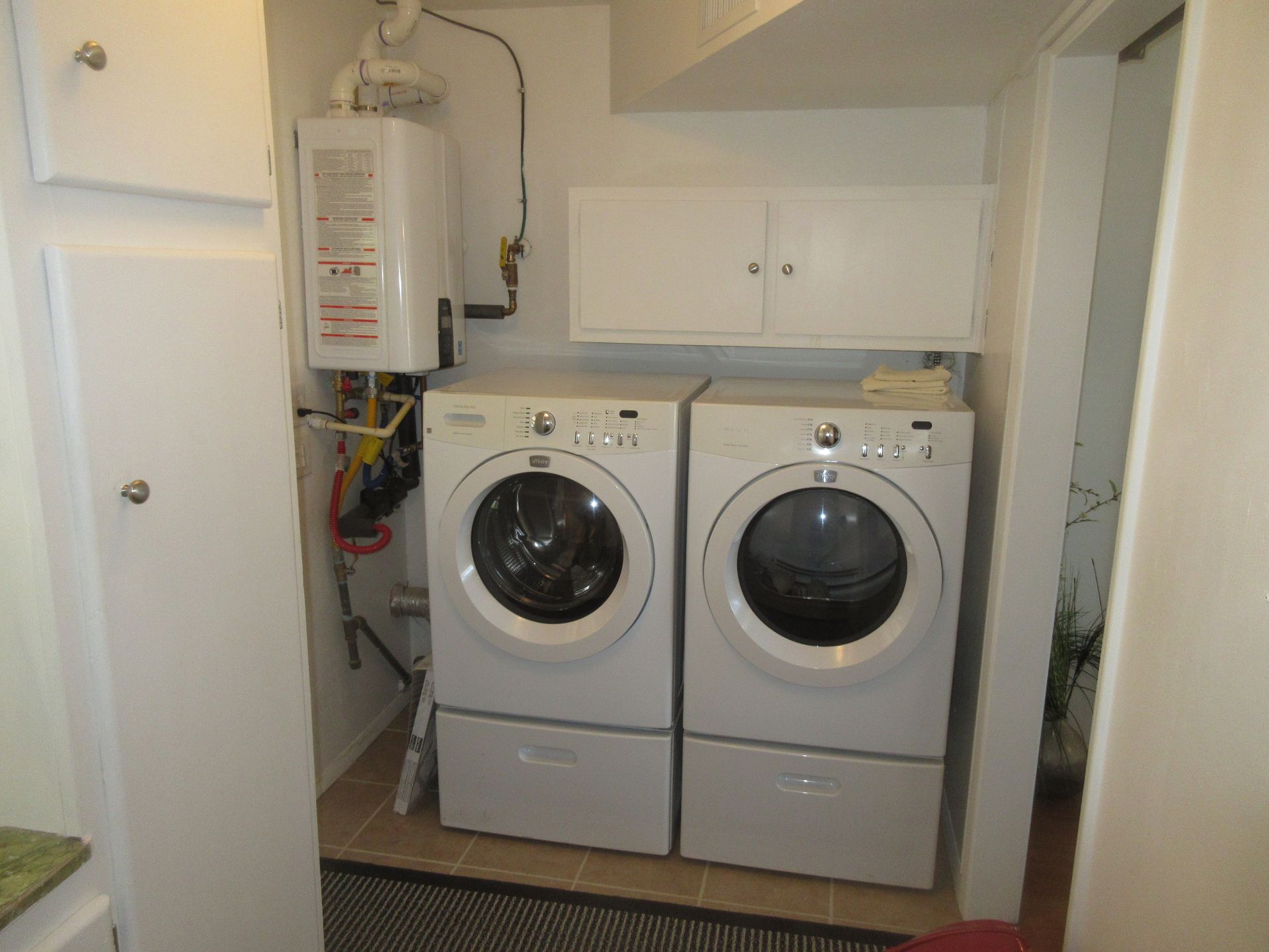 A laundry room with two white washers and dryers