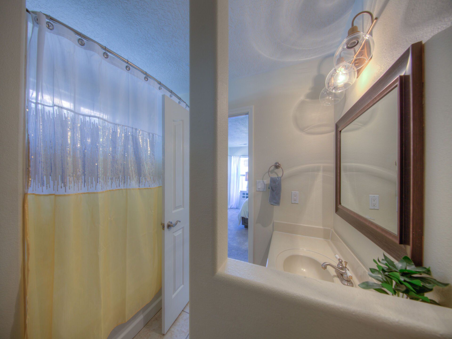A bathroom with a sink , mirror and shower curtain.