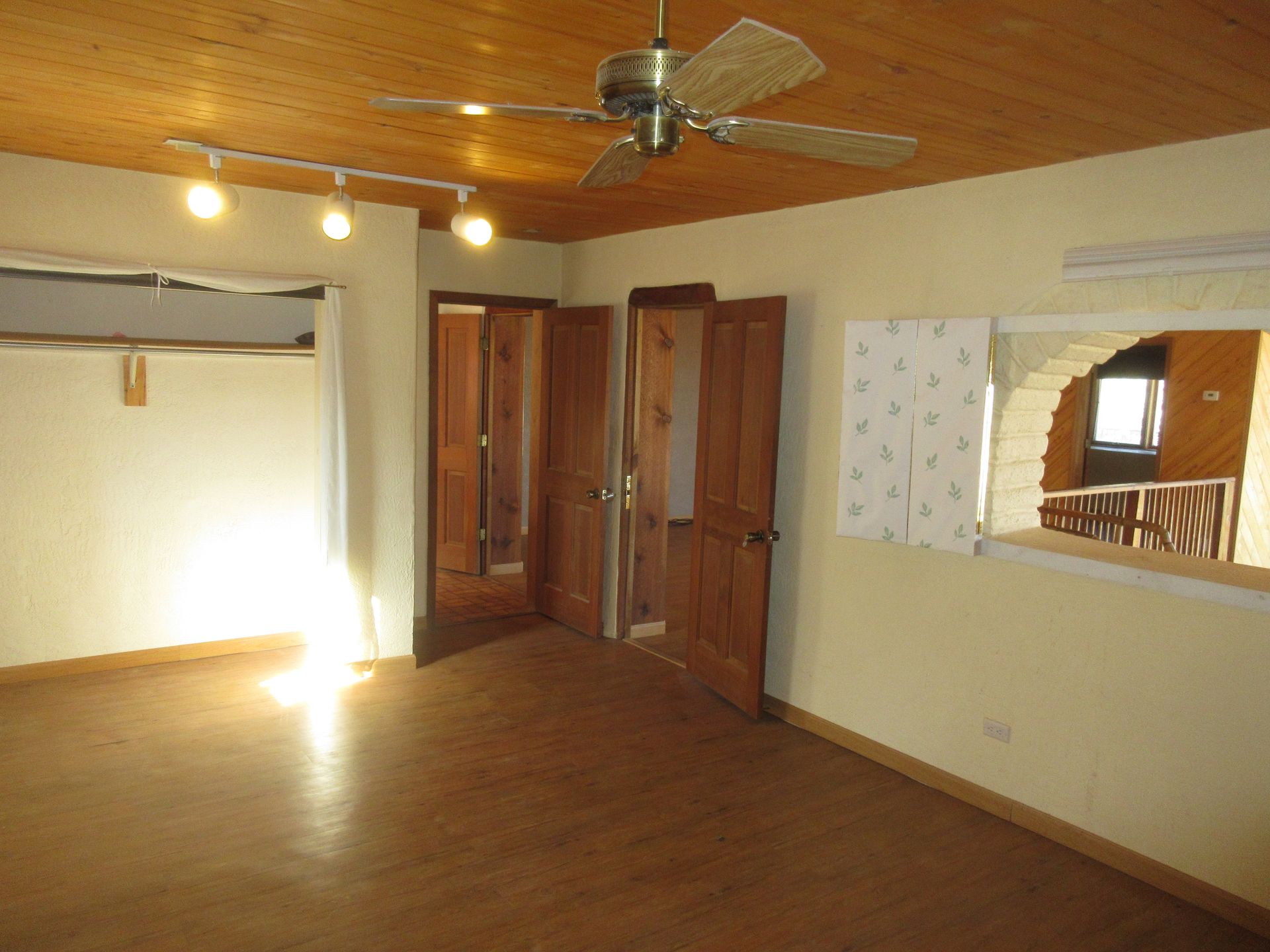 An empty room with a ceiling fan and a mirror