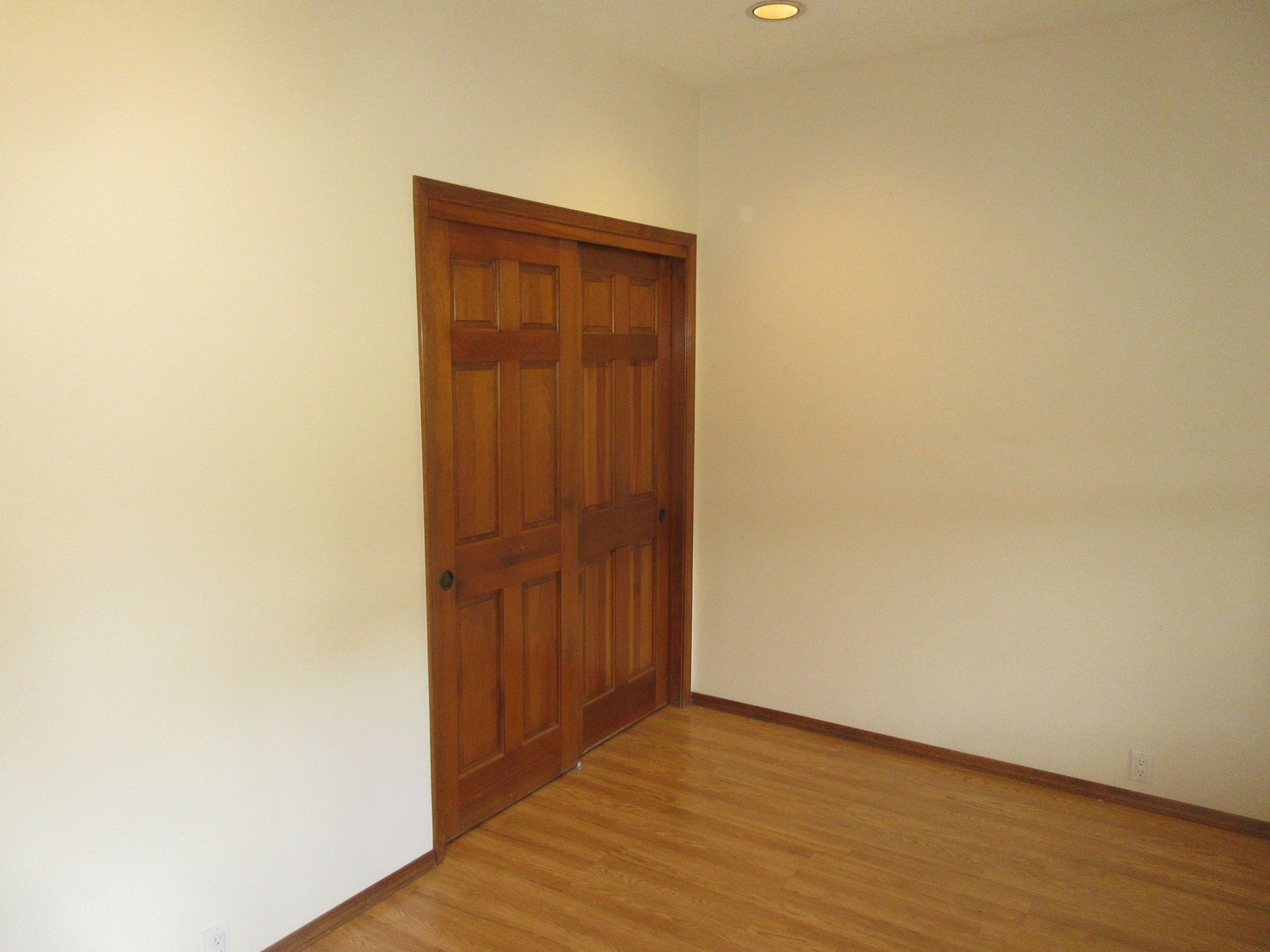An empty room with a wooden floor and a wooden door.