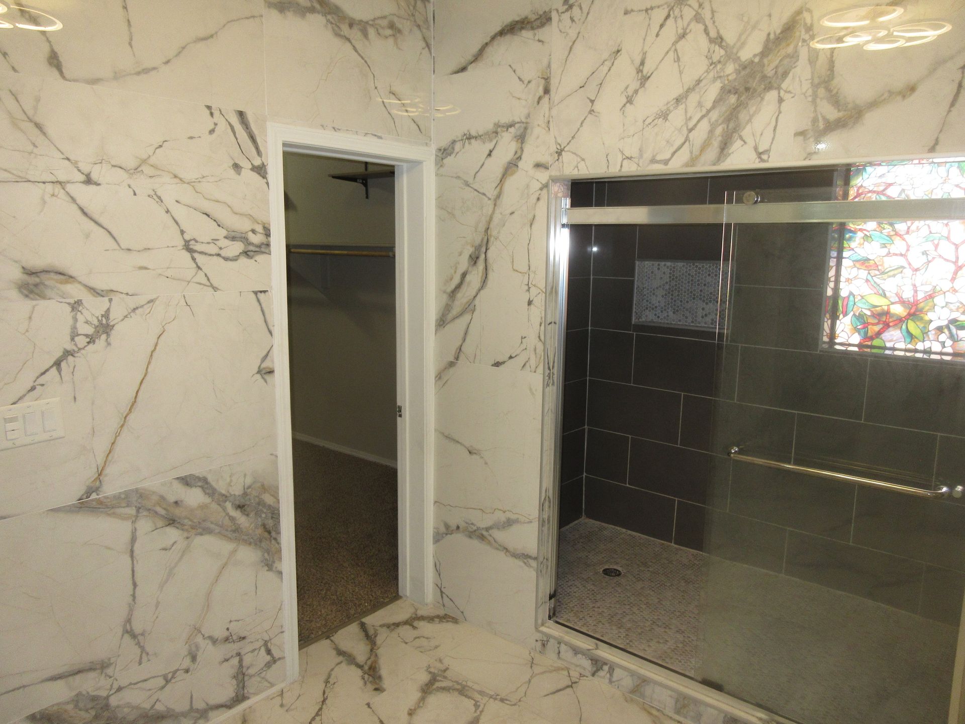 A bathroom with marble walls and a walk in shower.