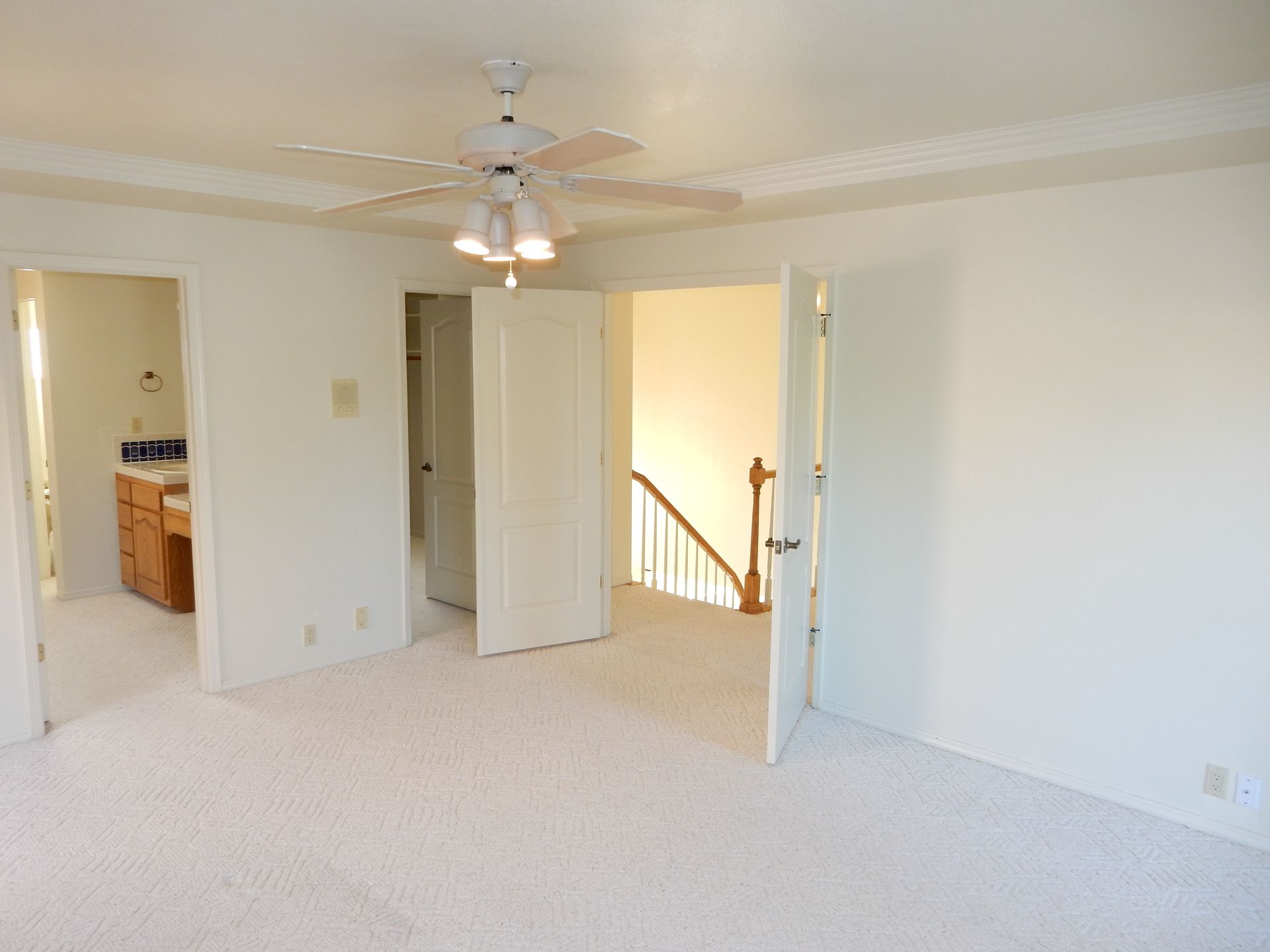 An empty room with a ceiling fan and stairs