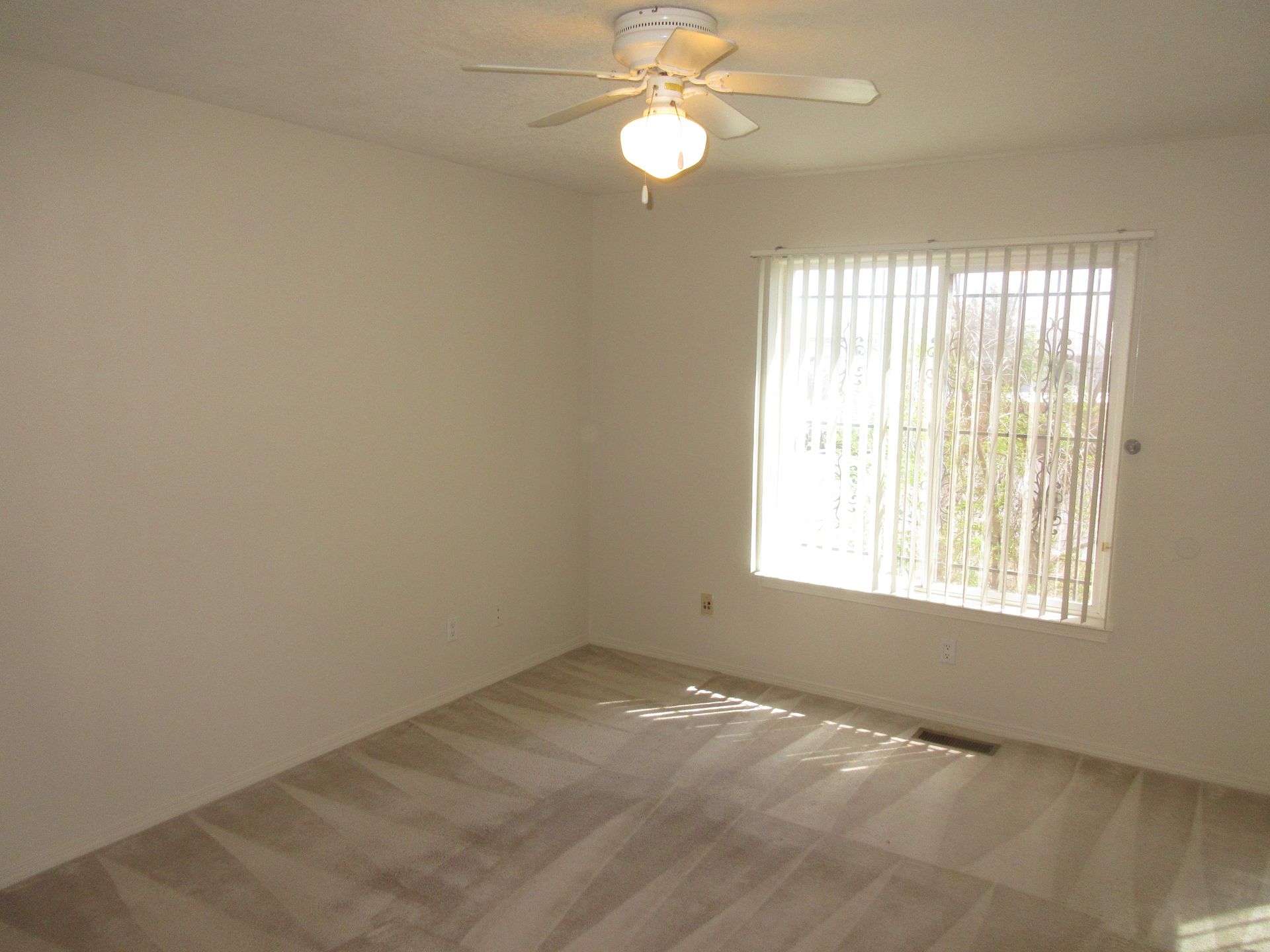 An empty room with a ceiling fan and a window