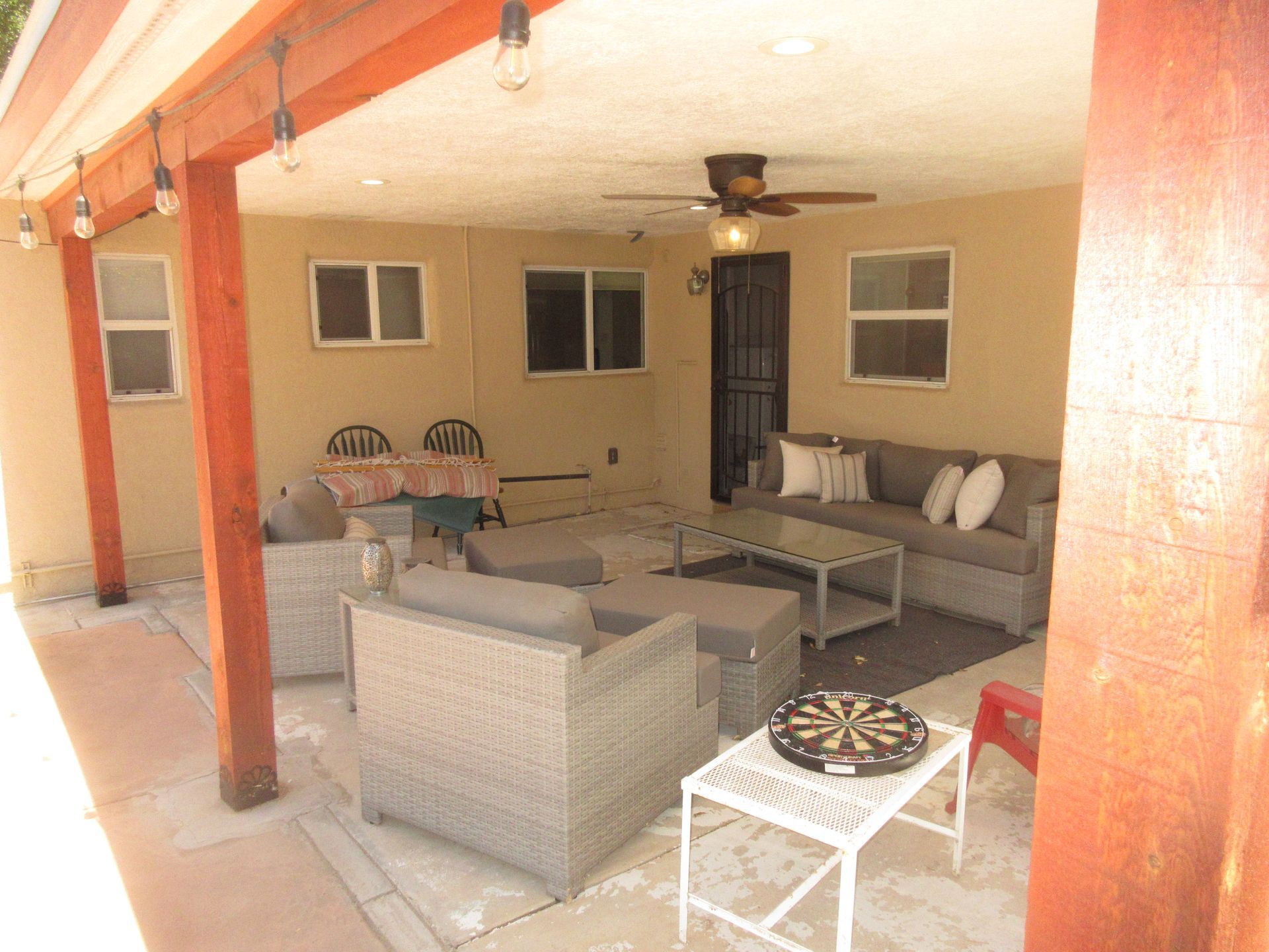 A patio with a lot of furniture and a dart board