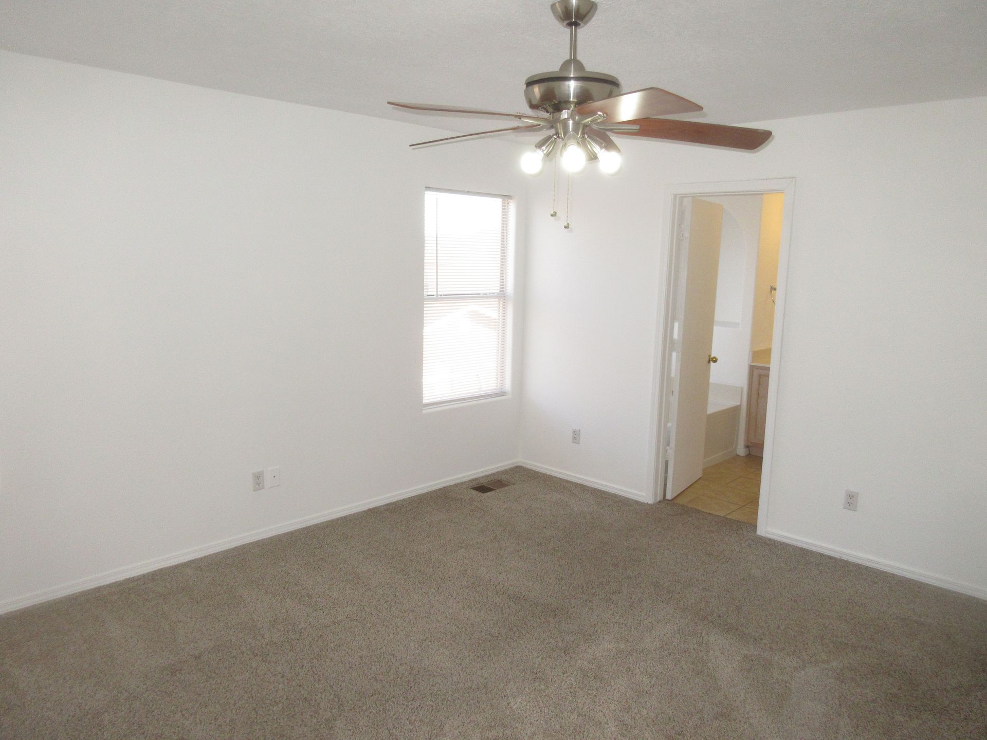 An empty bedroom with a ceiling fan and a window
