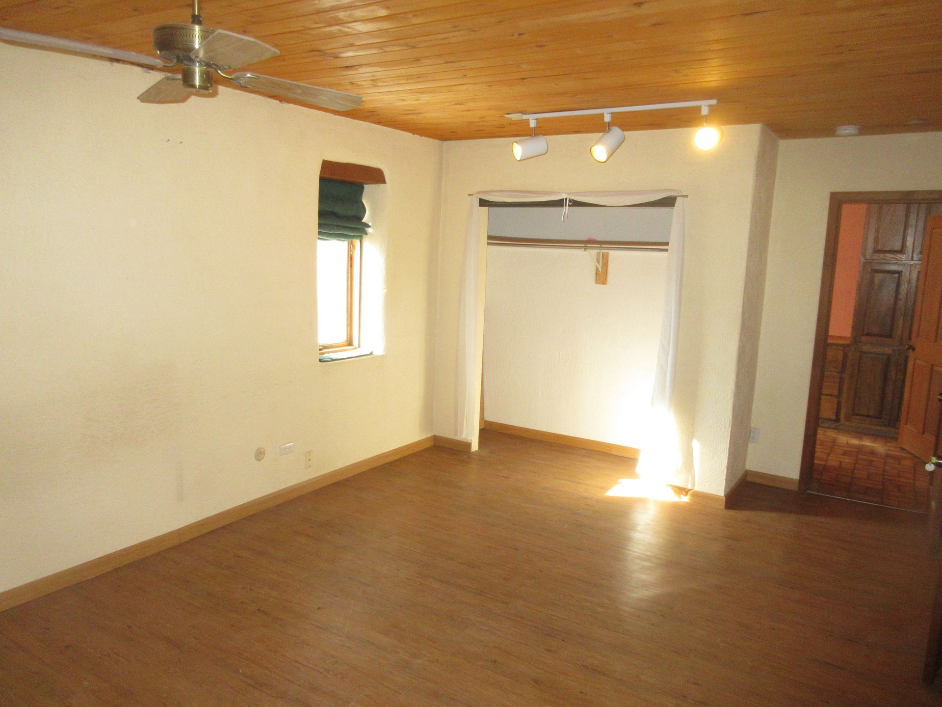 An empty room with a ceiling fan and a window