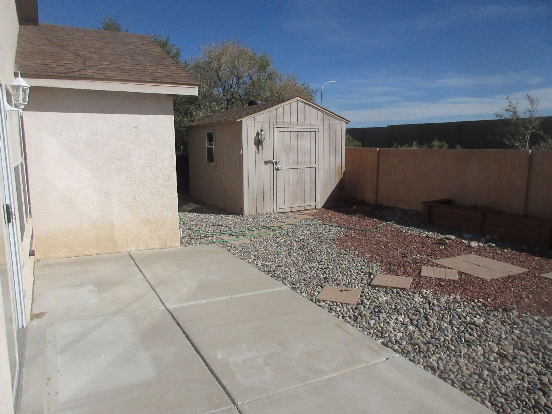 A backyard with a shed and a concrete walkway