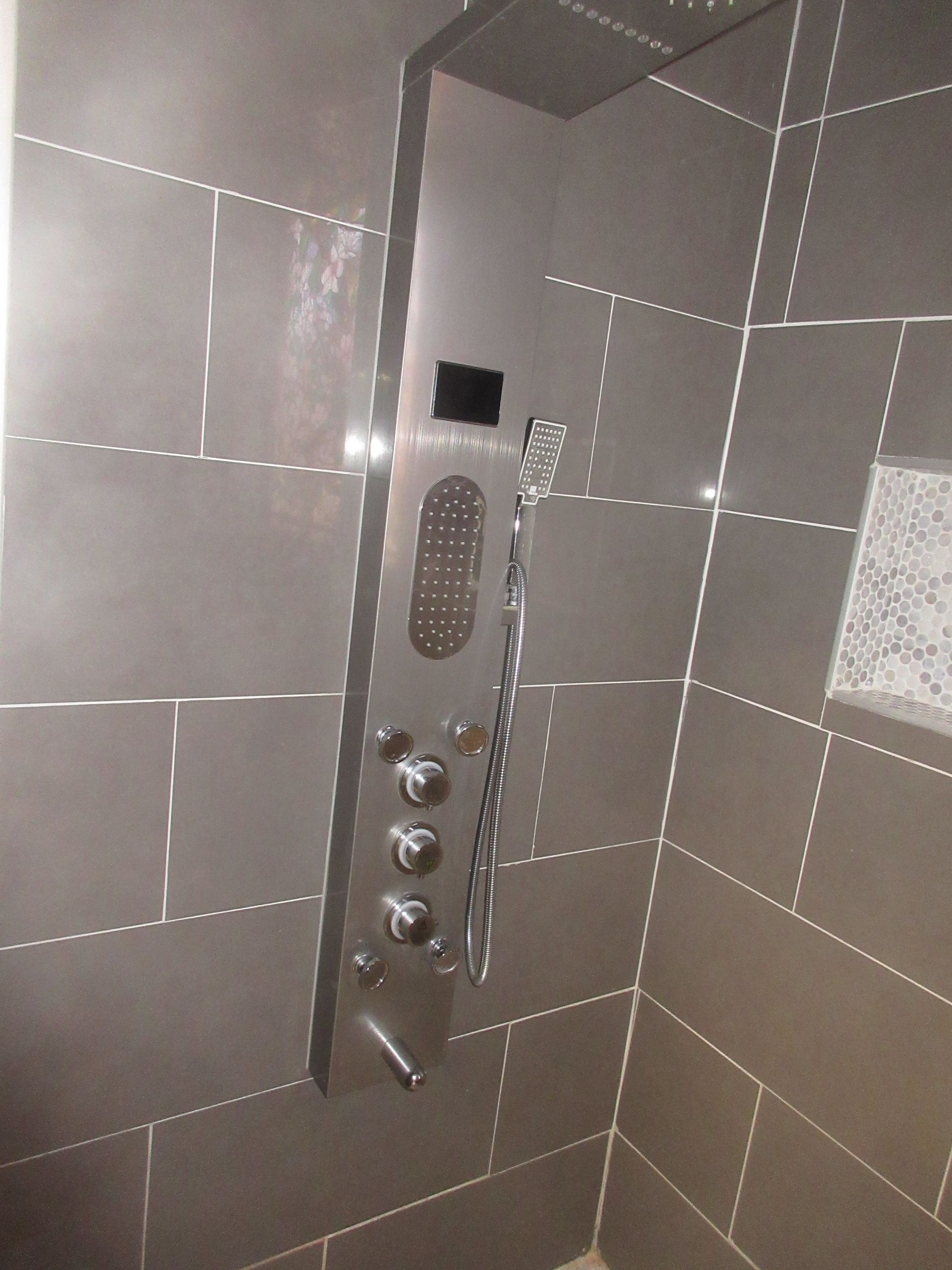 A shower stall with a stainless steel shower head
