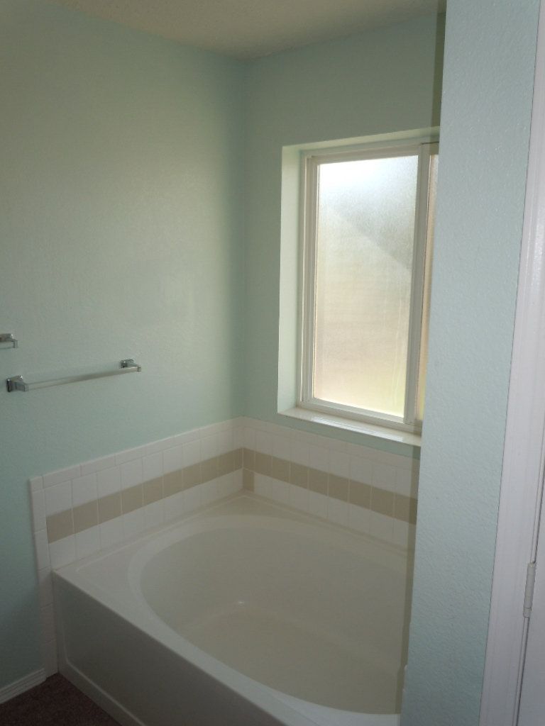 A bathtub in a bathroom next to a window.