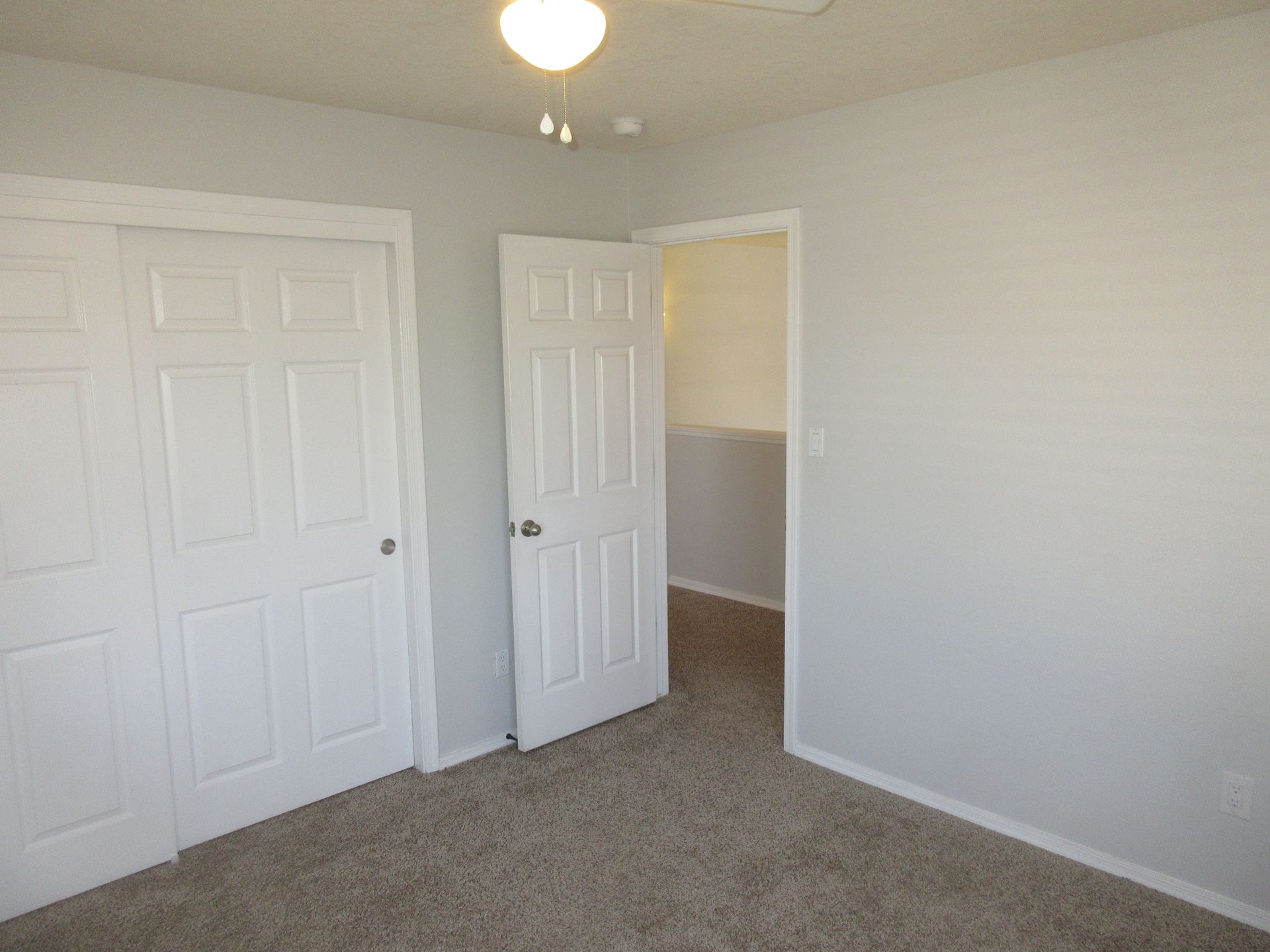 An empty bedroom with a ceiling fan and a closet.