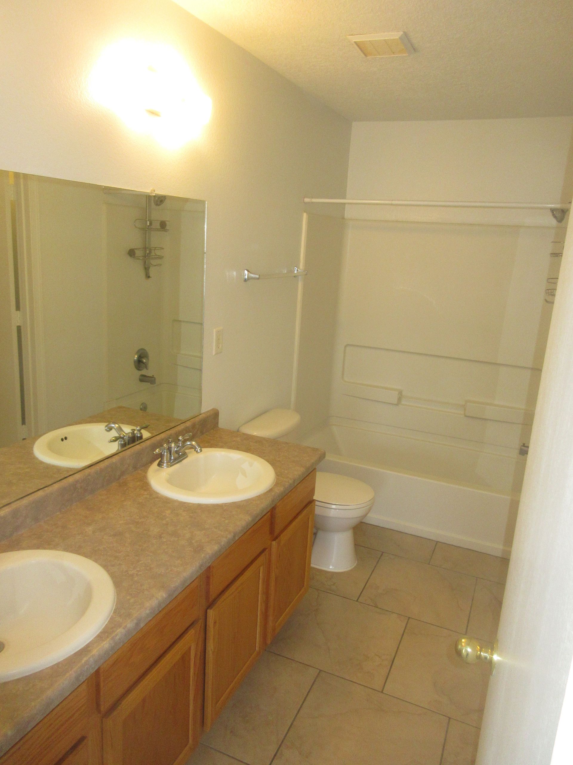 A bathroom with two sinks , a toilet , and a shower.