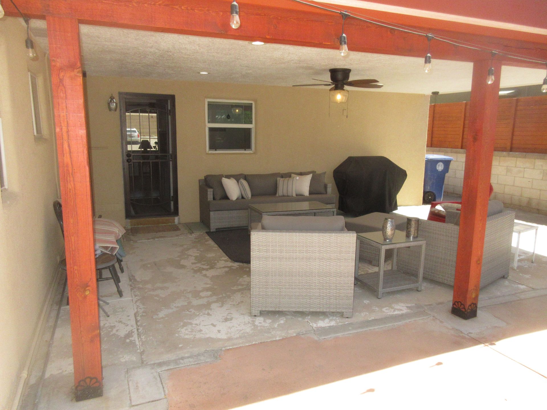 A patio with a couch , chairs , tables and a ceiling fan.