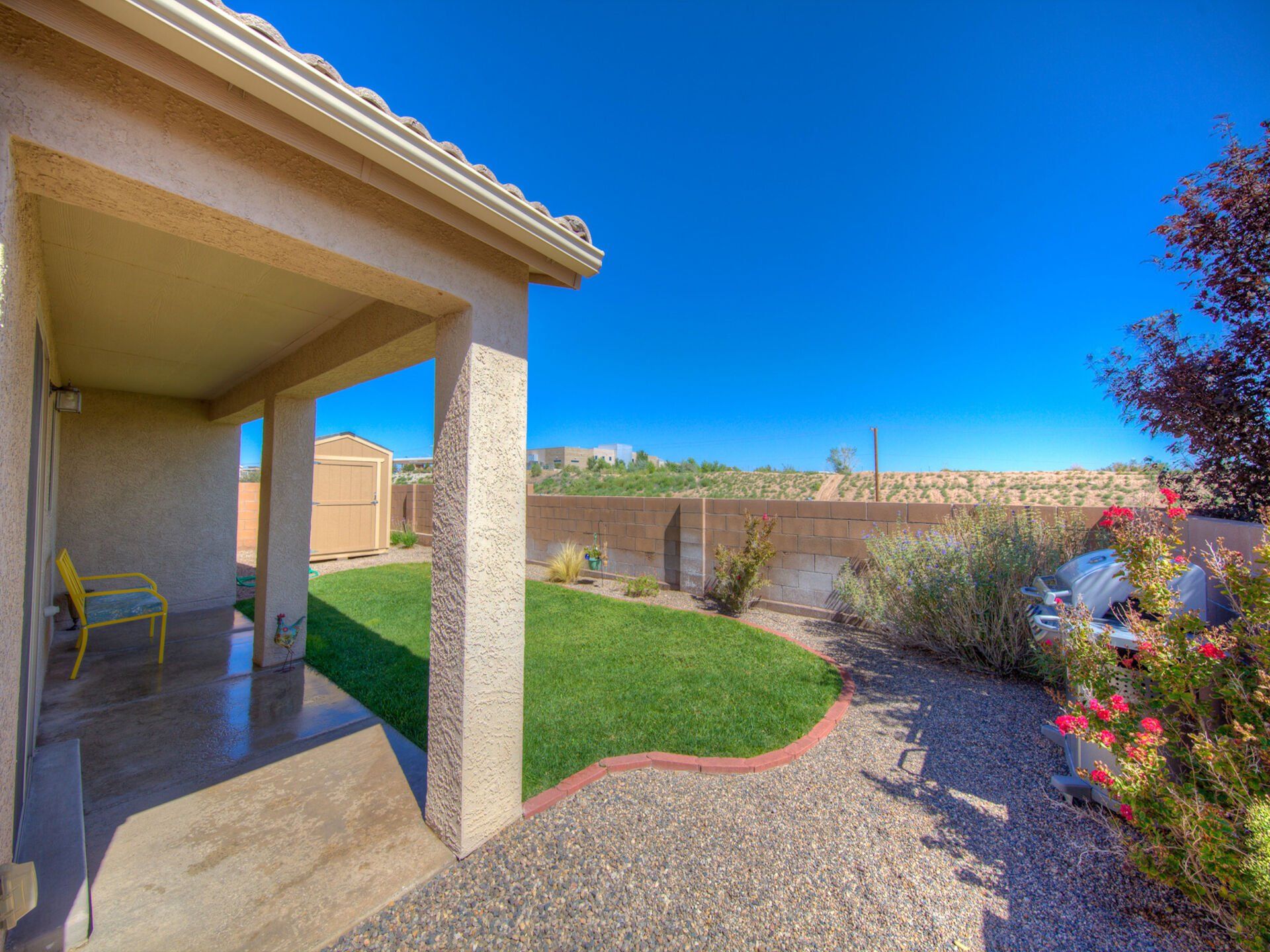 The backyard of a house with a covered patio and a lush green lawn.