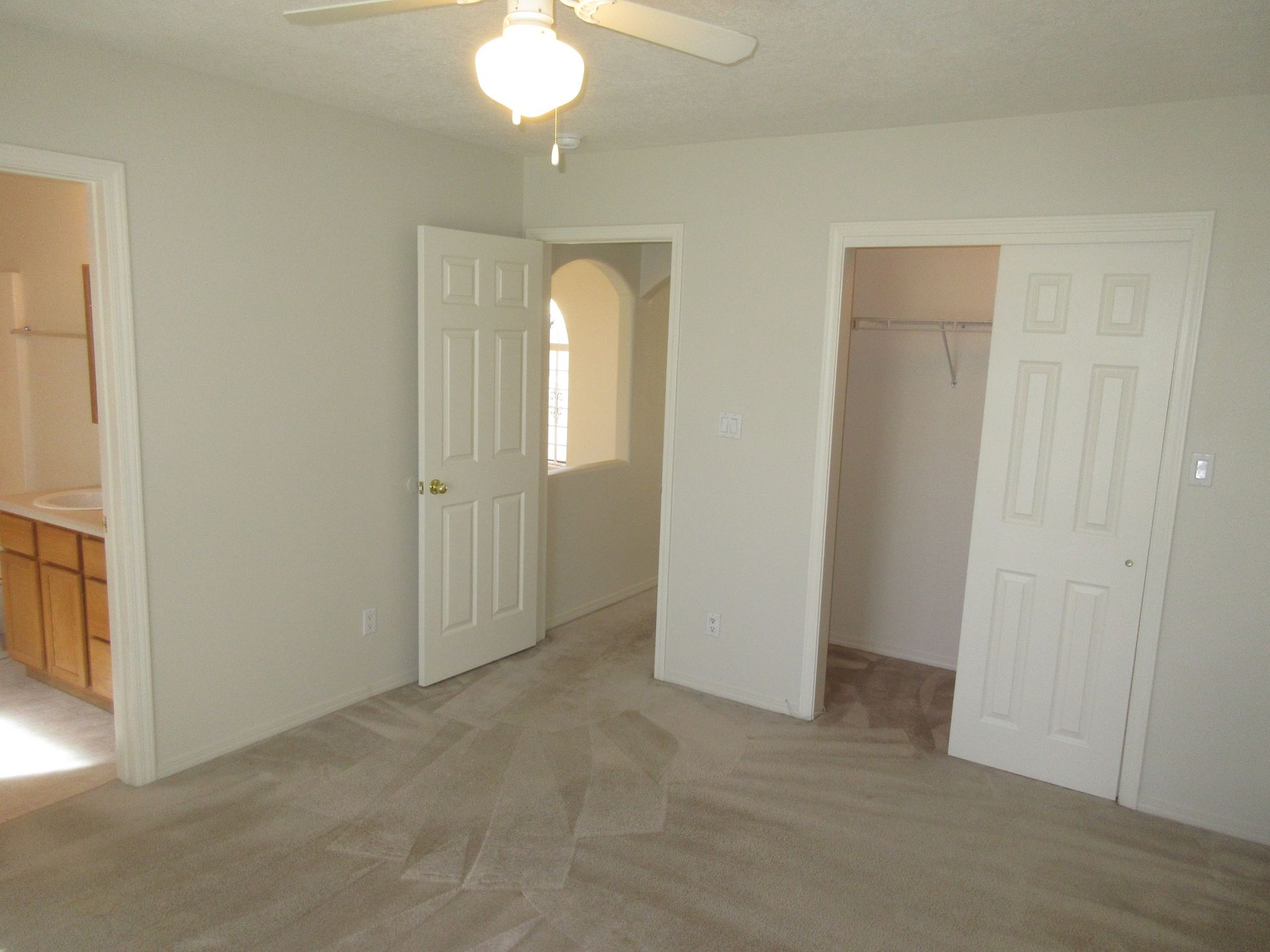 An empty bedroom with a ceiling fan and a walk in closet.