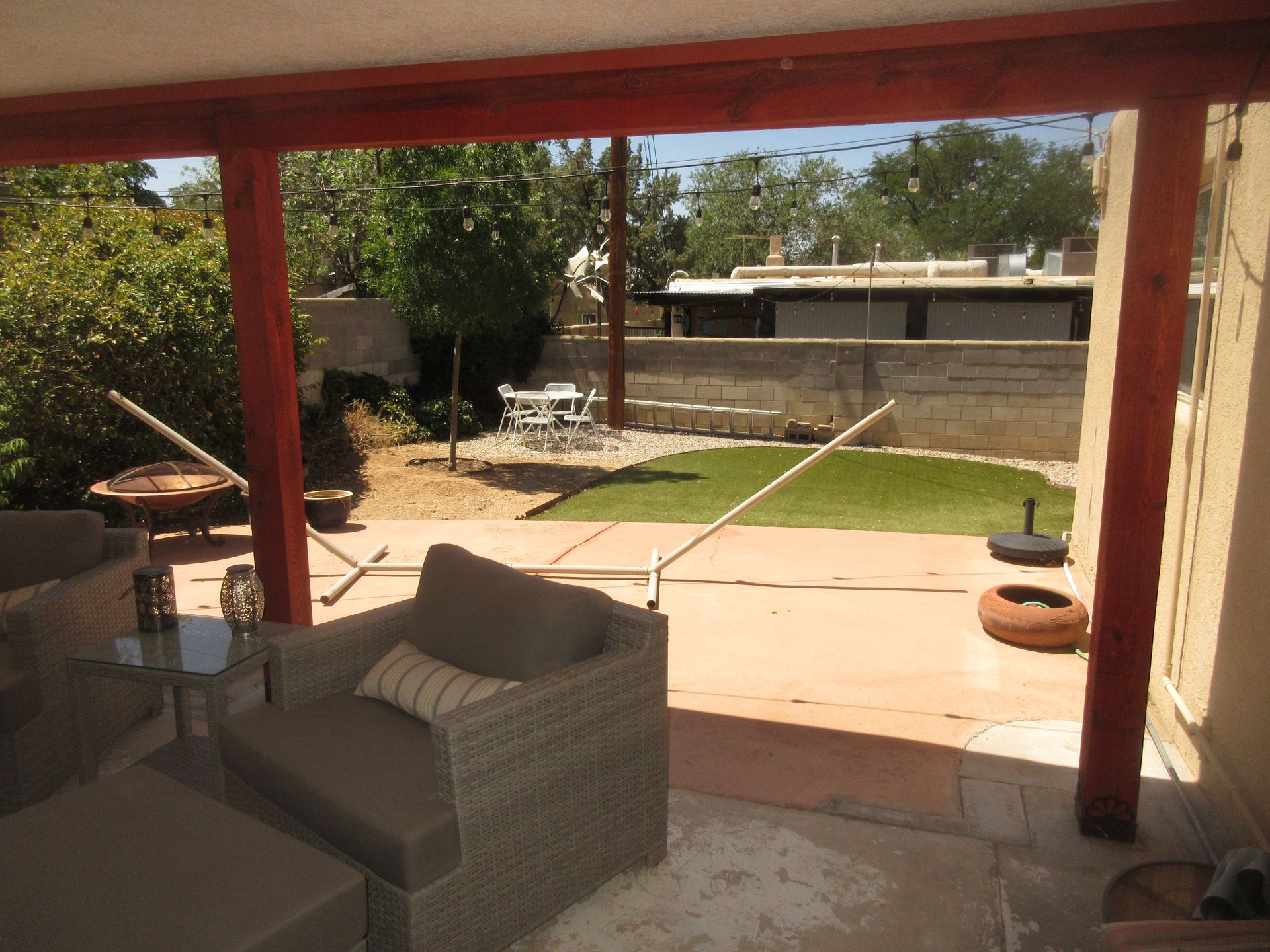 A patio with wicker furniture and a view of a backyard