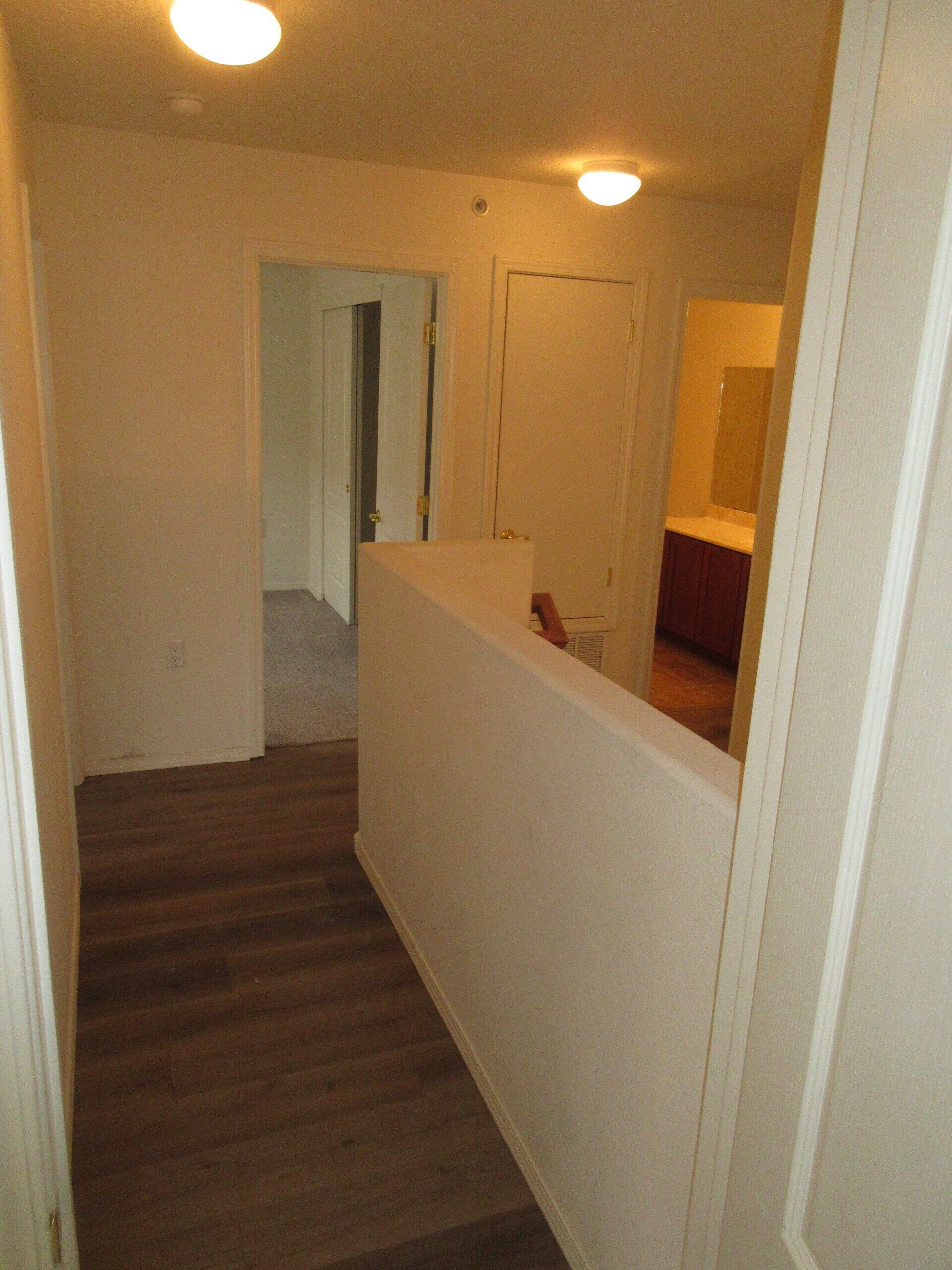 A hallway with hardwood floors and a white wall