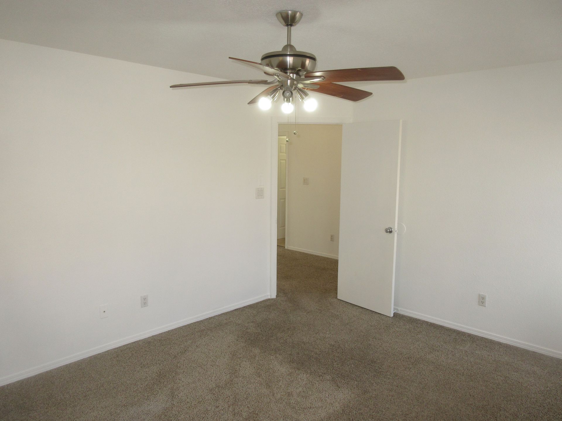 An empty bedroom with a ceiling fan hanging from the ceiling