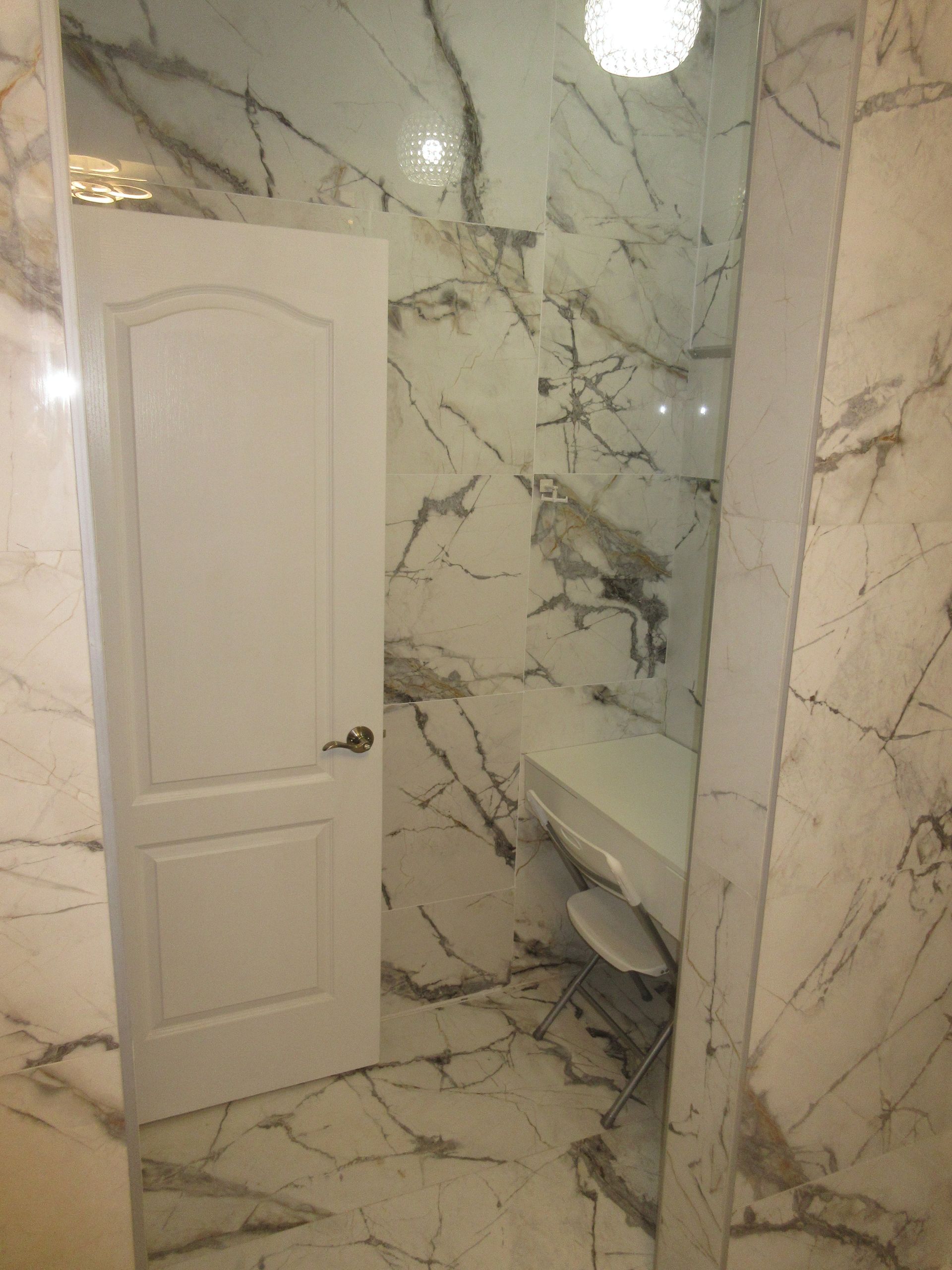 A bathroom with marble walls and a white door