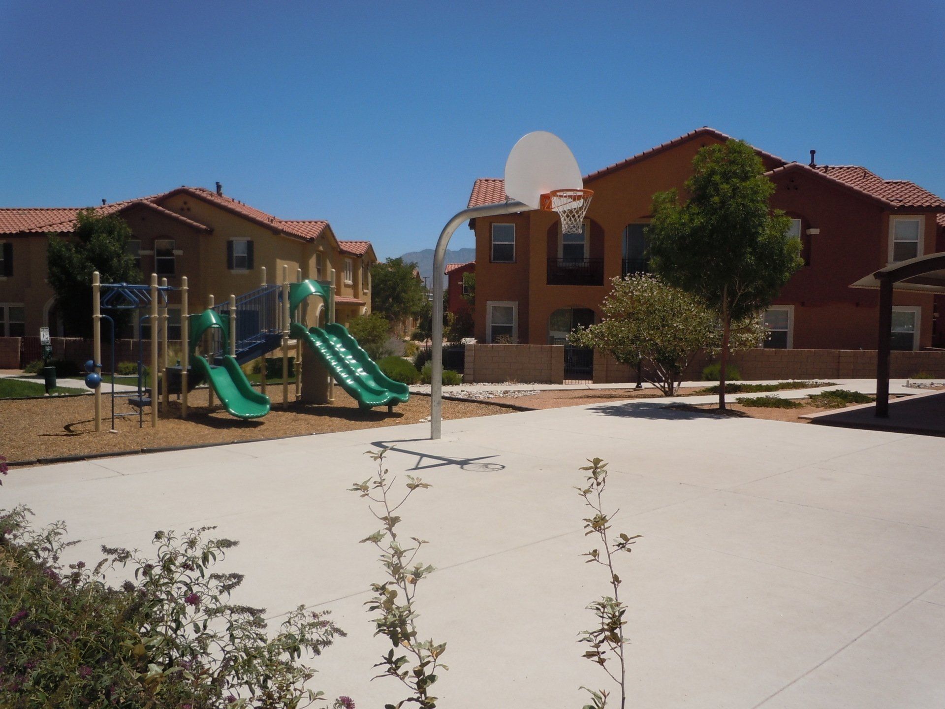 A playground with a basketball hoop and a slide