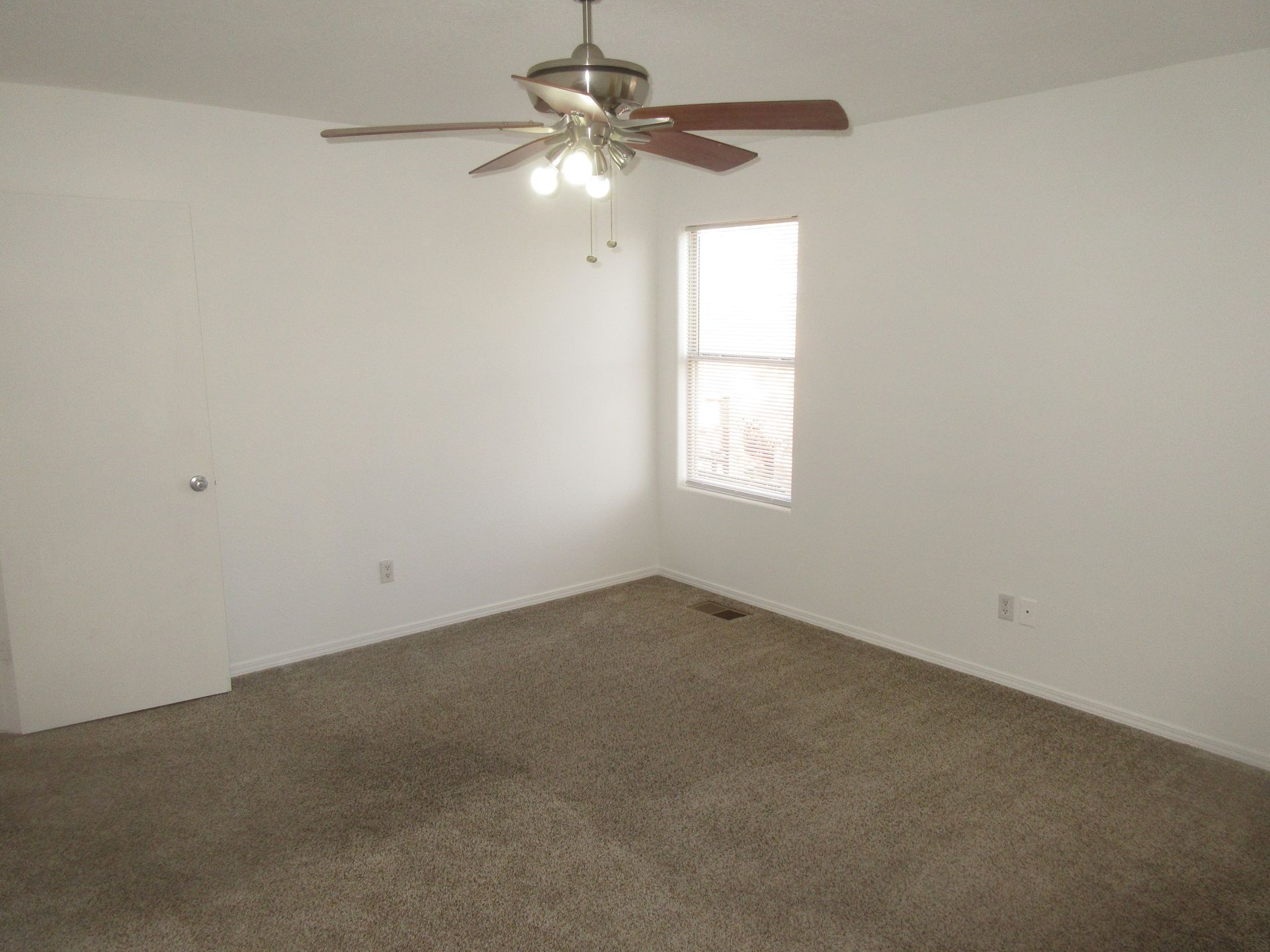 An empty bedroom with a ceiling fan and a window.