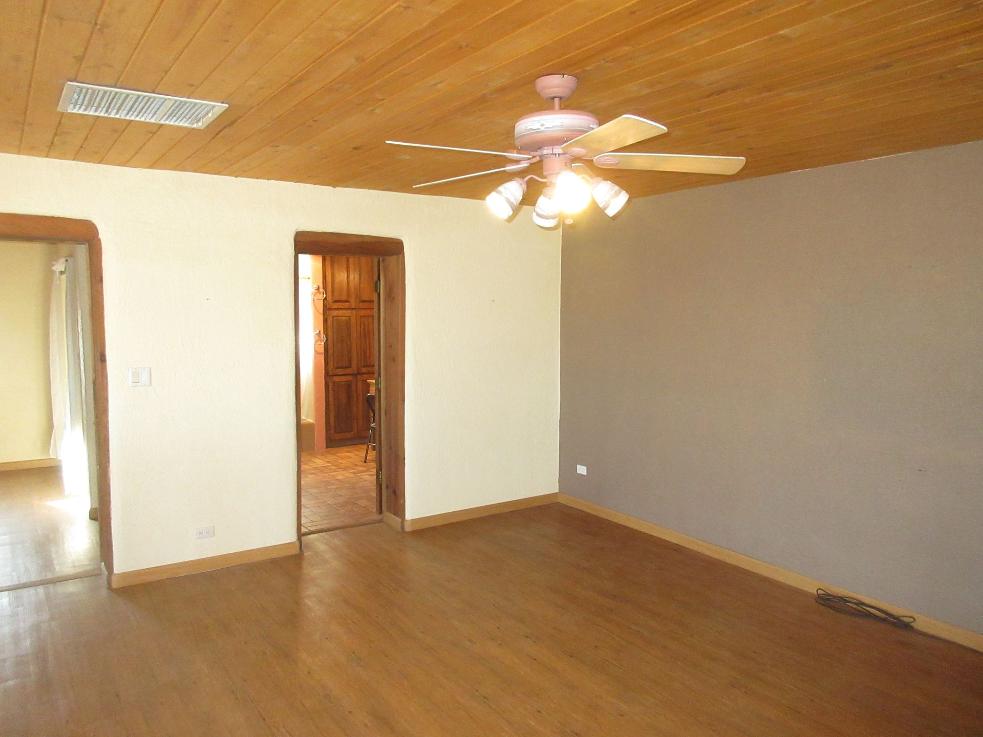 An empty living room with a wooden floor and a ceiling fan.