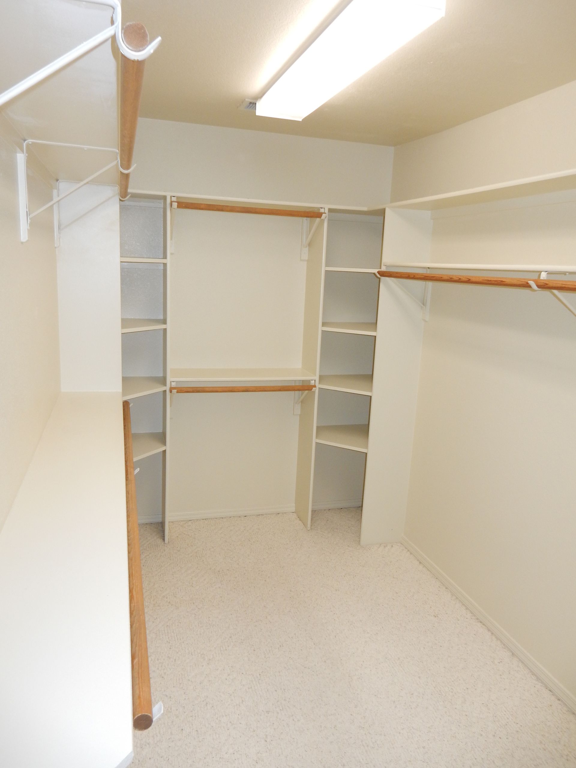 A walk in closet with lots of shelves and hangers