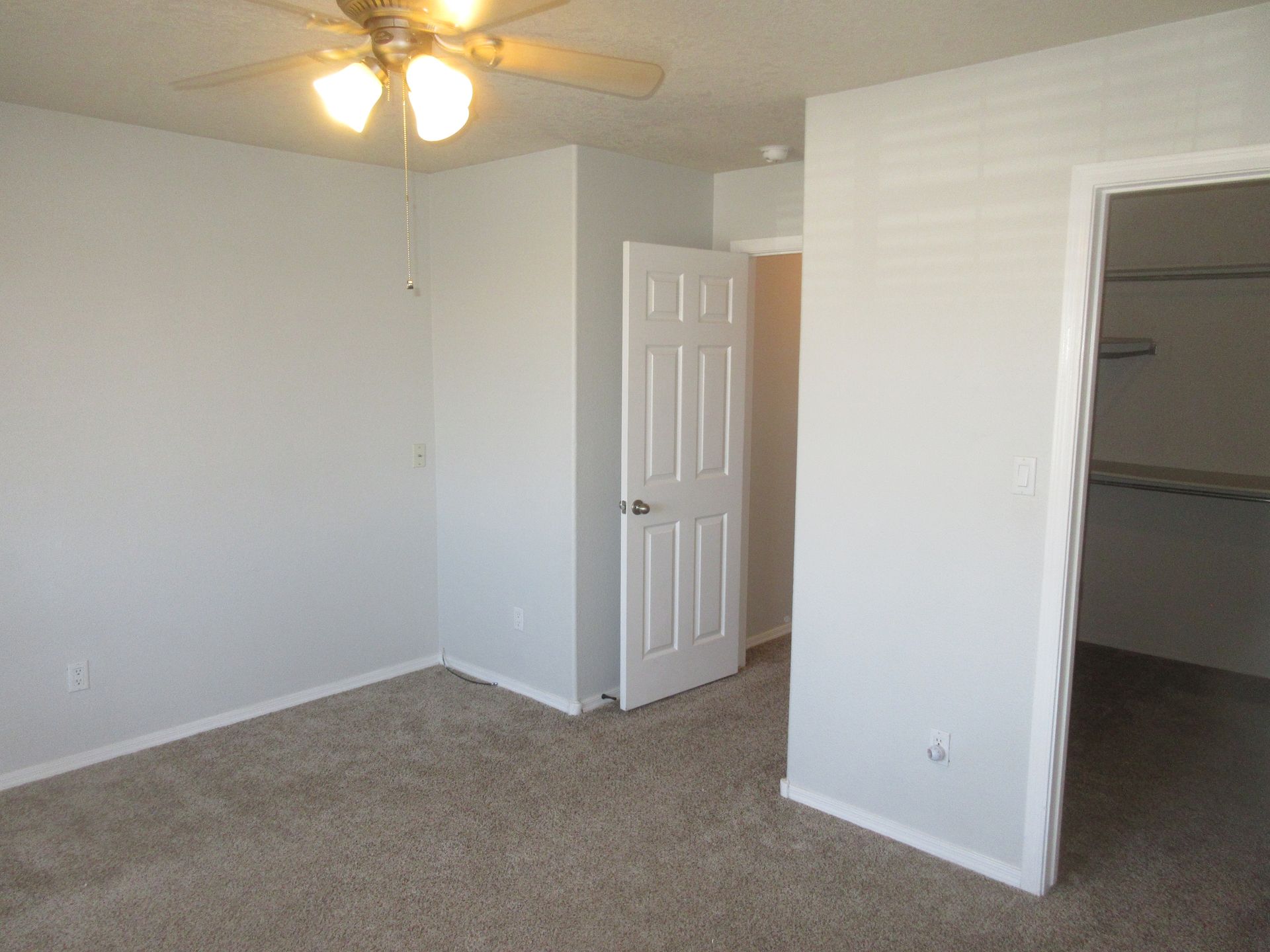An empty bedroom with a ceiling fan and a walk in closet