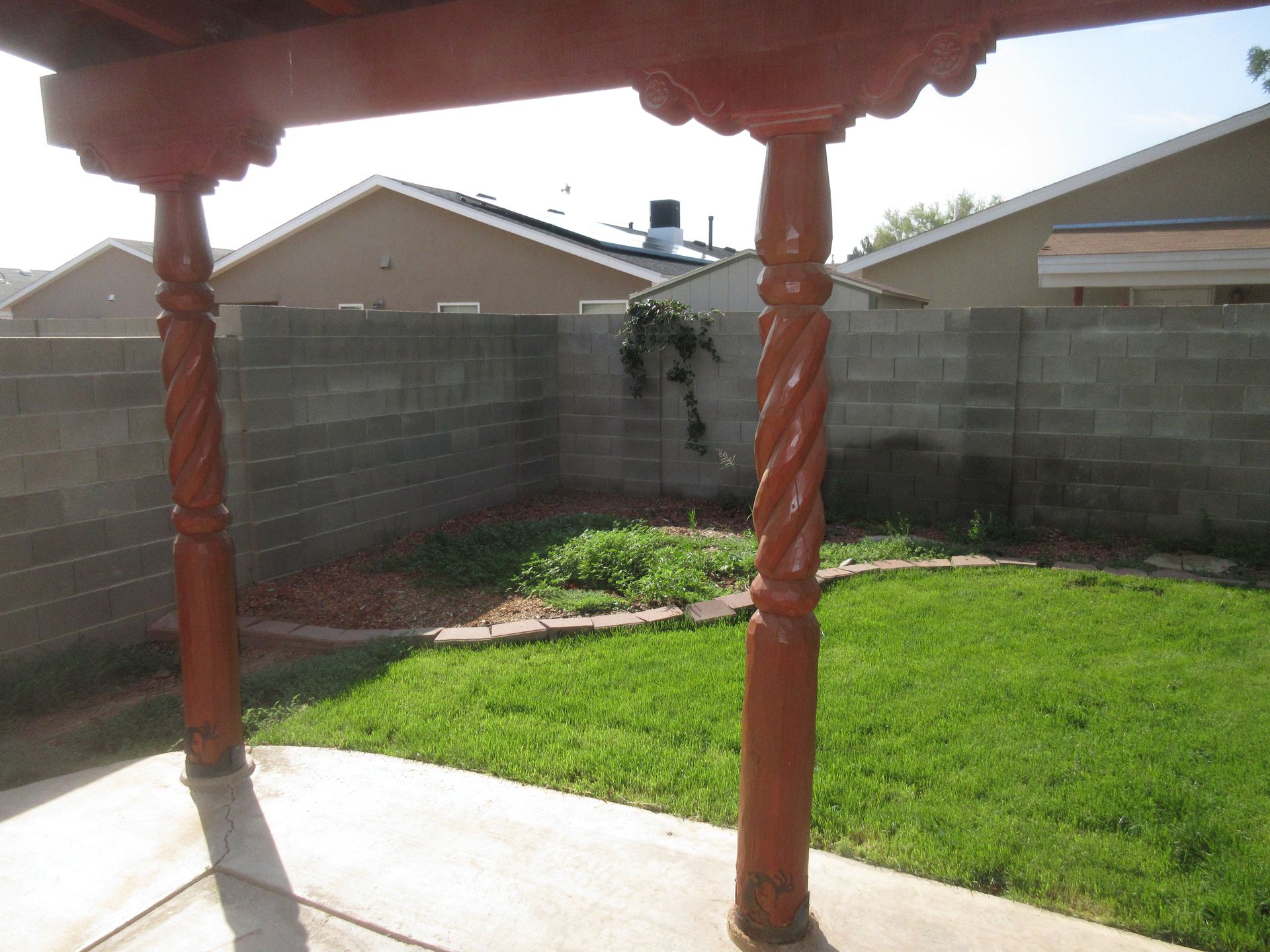 A backyard with a pergola and a brick wall