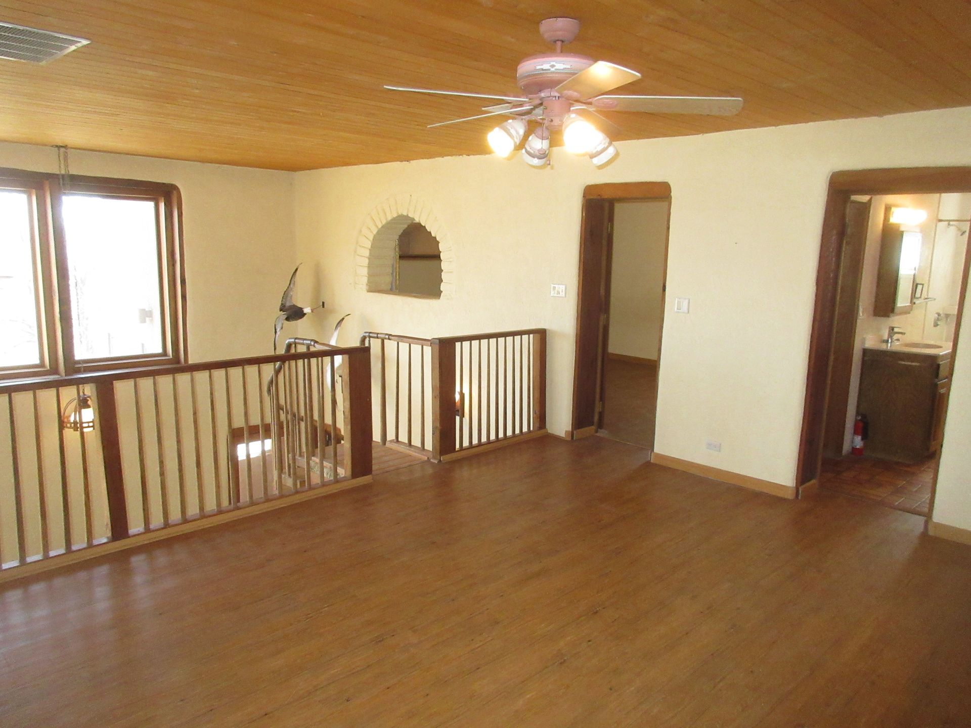 An empty room with a ceiling fan and a wooden floor.