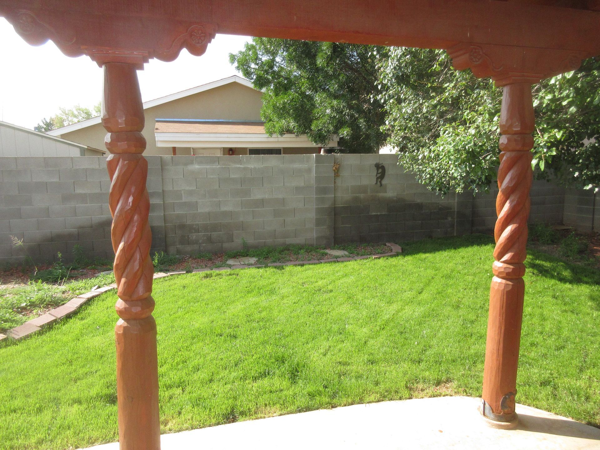 A backyard with a pergola and a brick wall