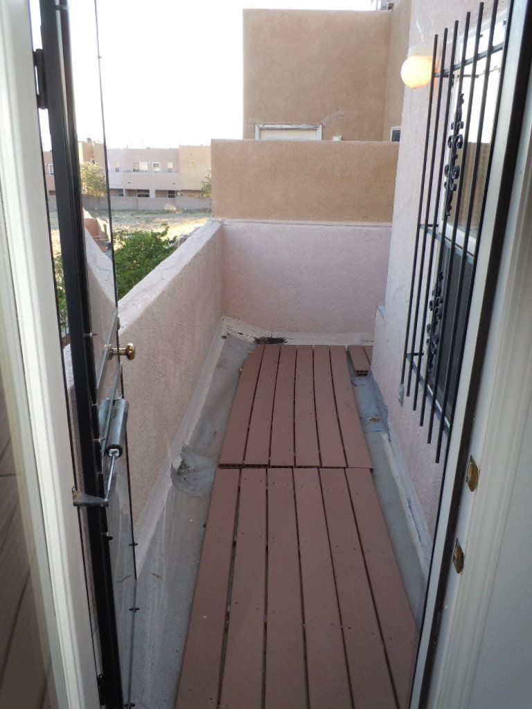 A balcony with a wooden floor and a fence