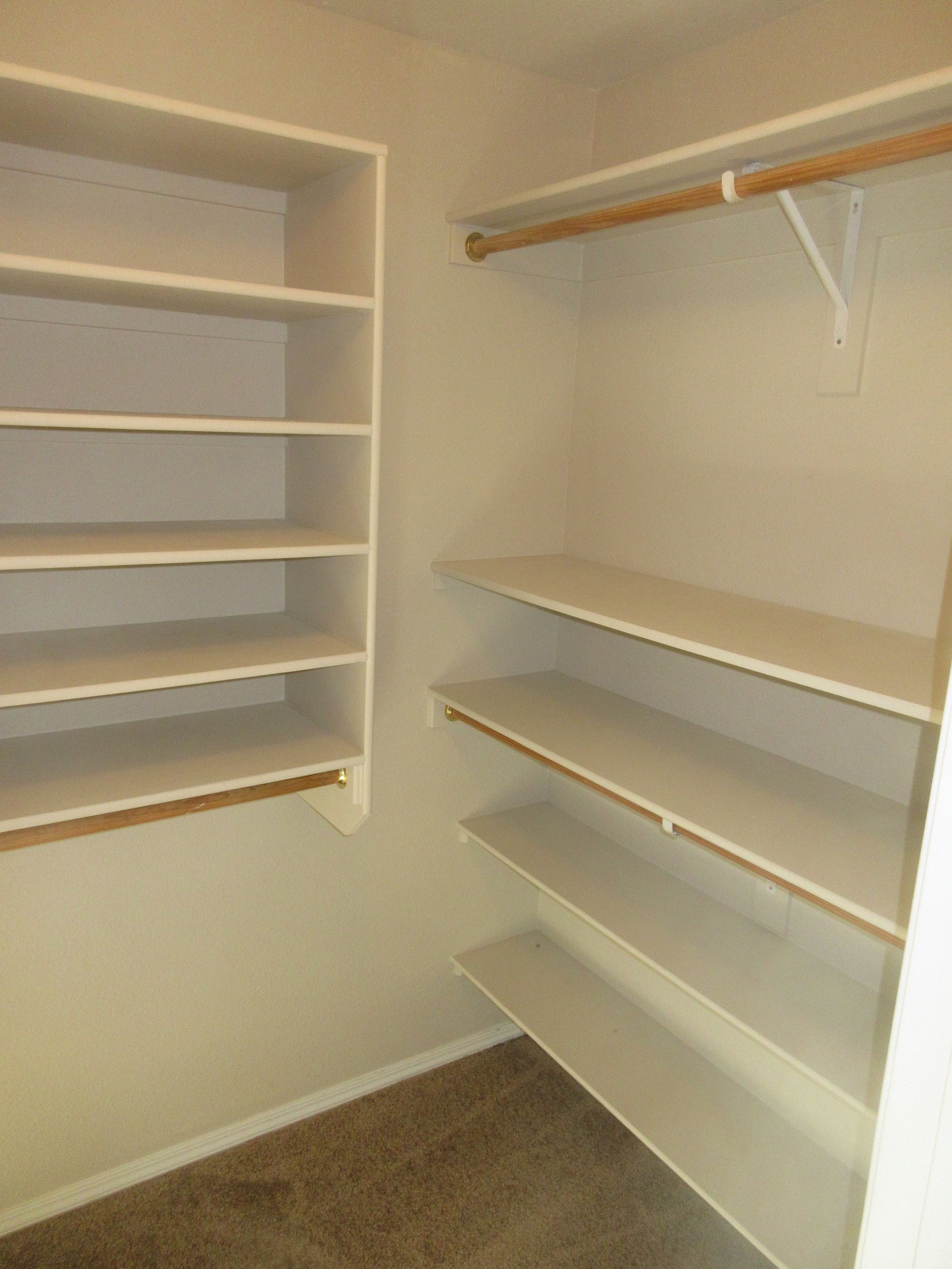 A walk in closet with lots of shelves and clothes racks