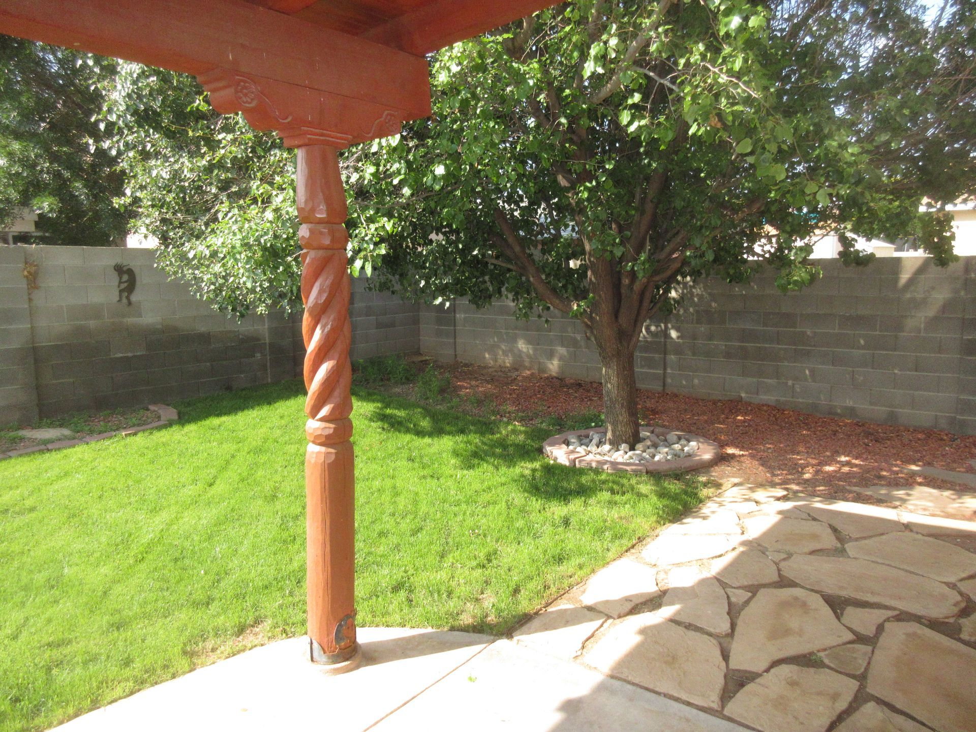 A patio with a wooden post and a tree in the backyard