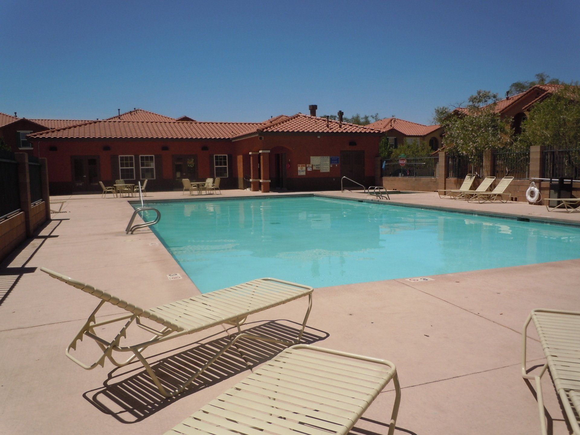 A large swimming pool surrounded by chairs and a building