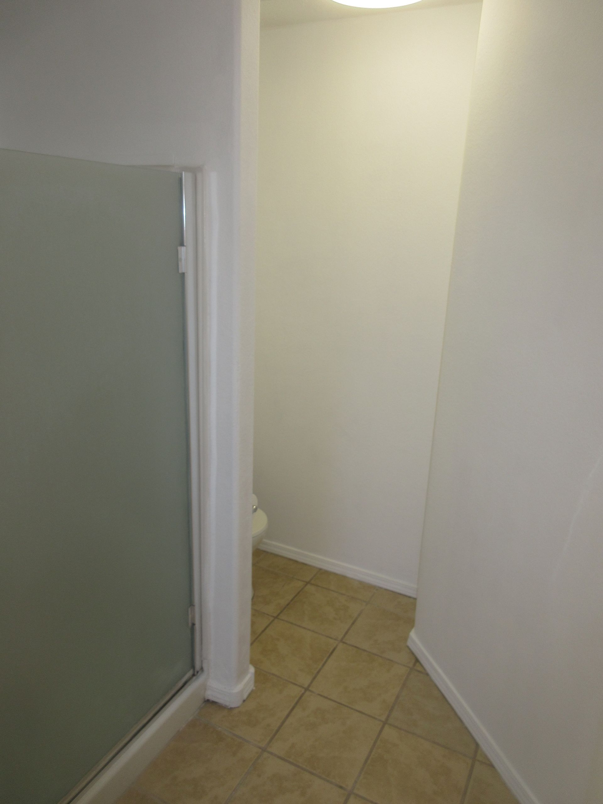 A hallway with a glass door leading to a bathroom.