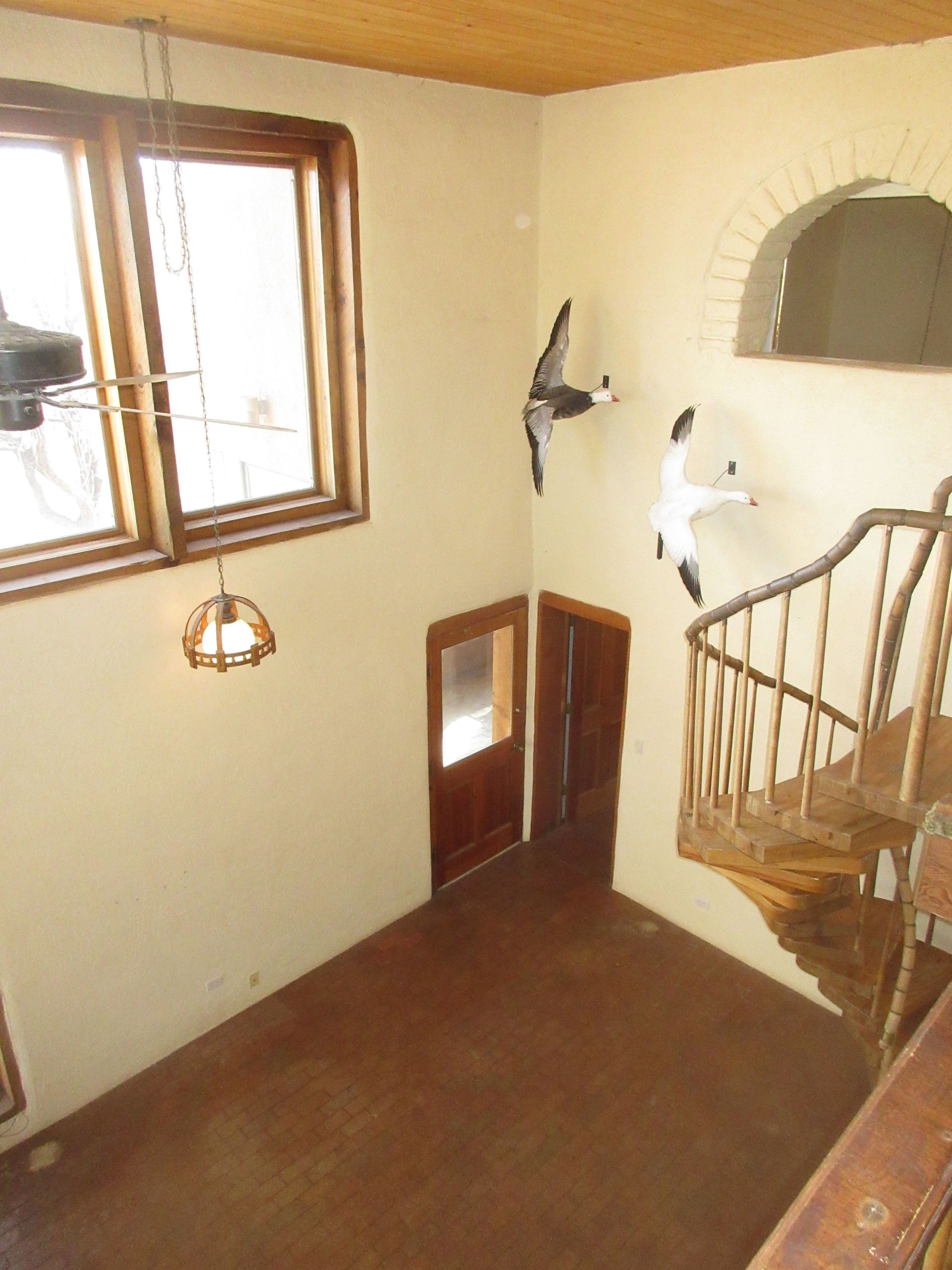 A room with a staircase and a bird on the wall