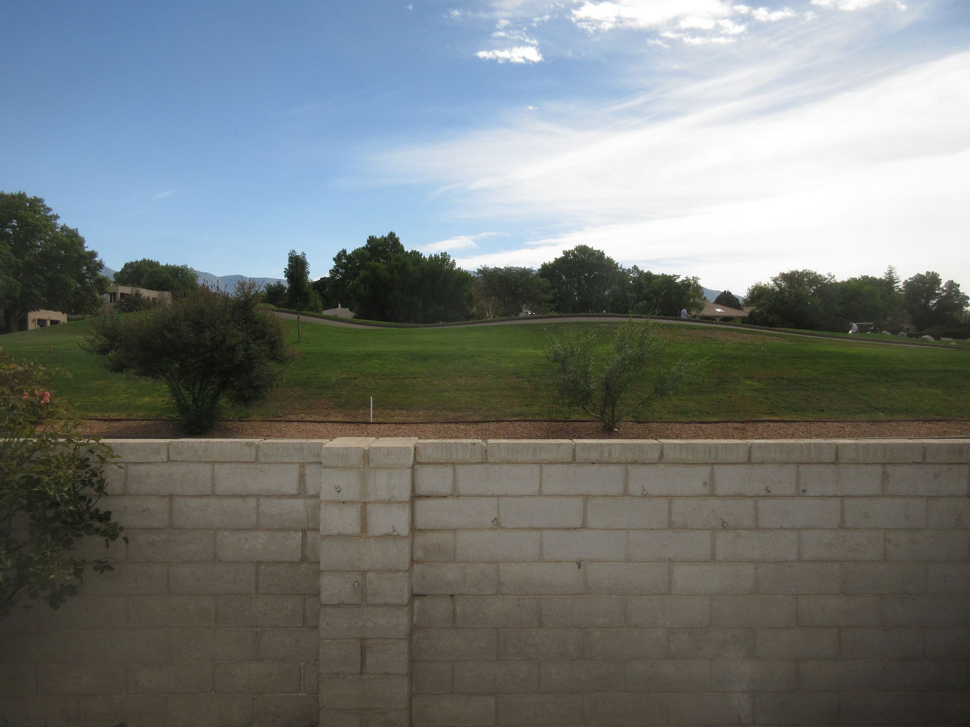 A brick wall with a view of a grassy field behind it
