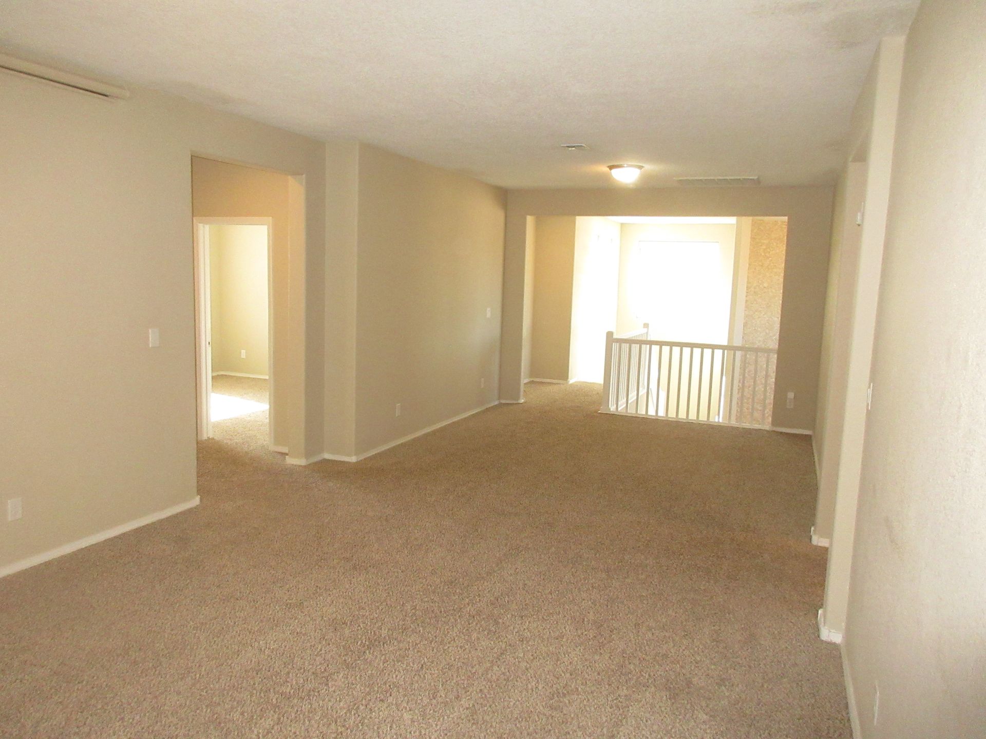 An empty living room with a staircase in the background