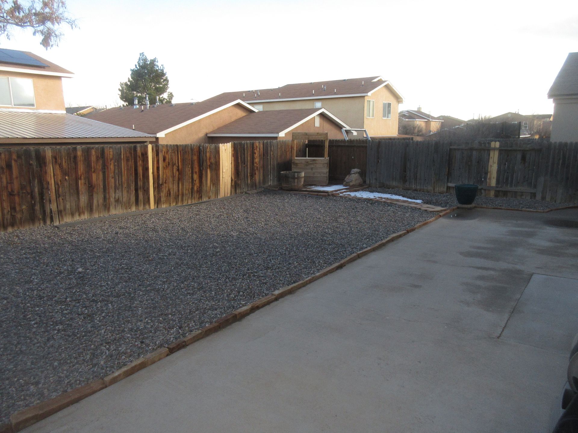 A gravel driveway leading to a house with a wooden fence
