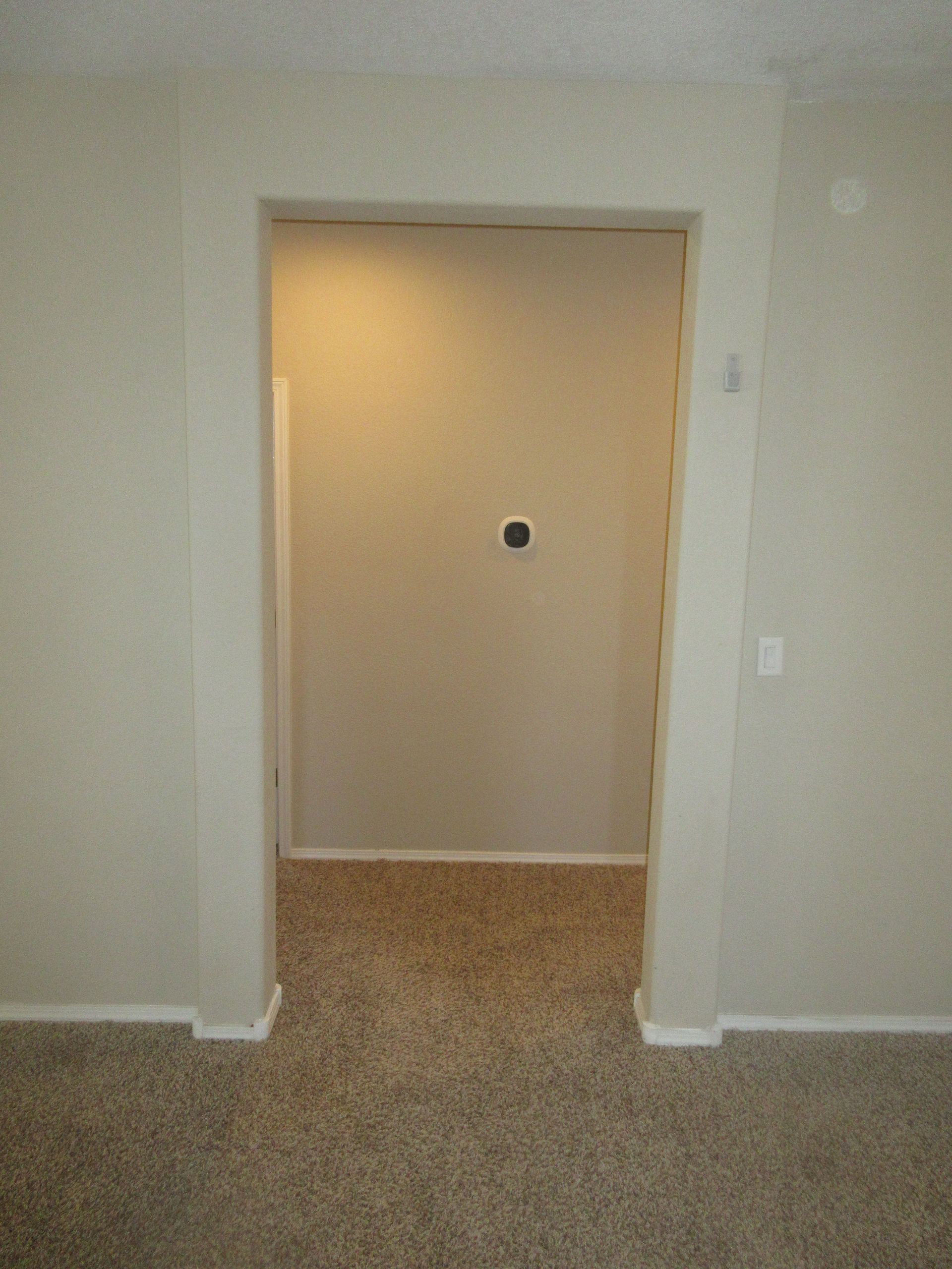 There is a door in the middle of a room with a carpeted floor.