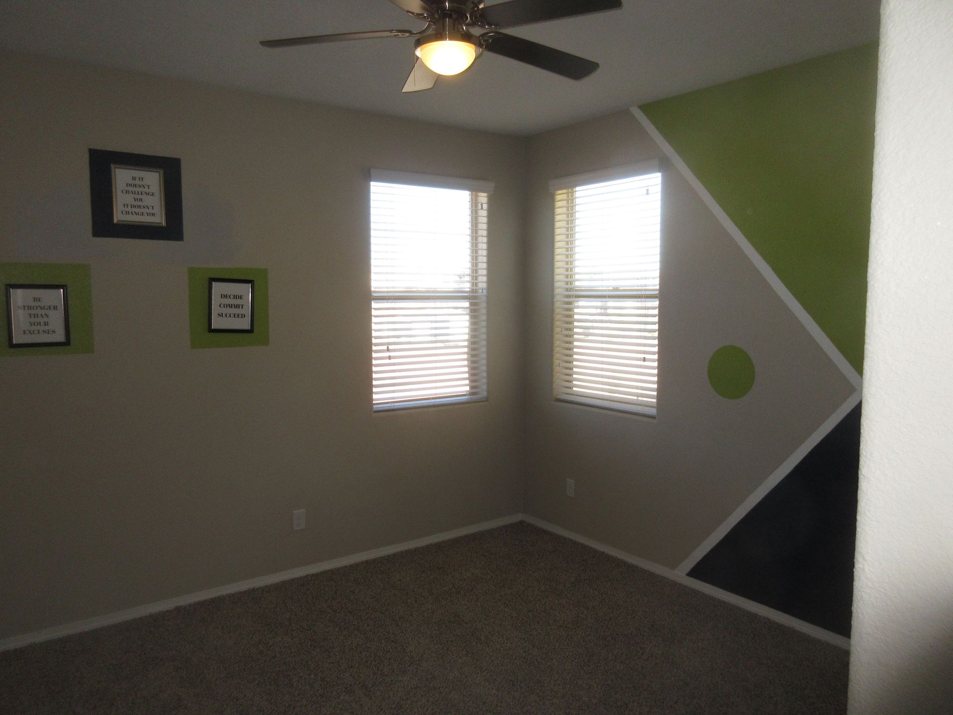 An empty room with a ceiling fan and three windows