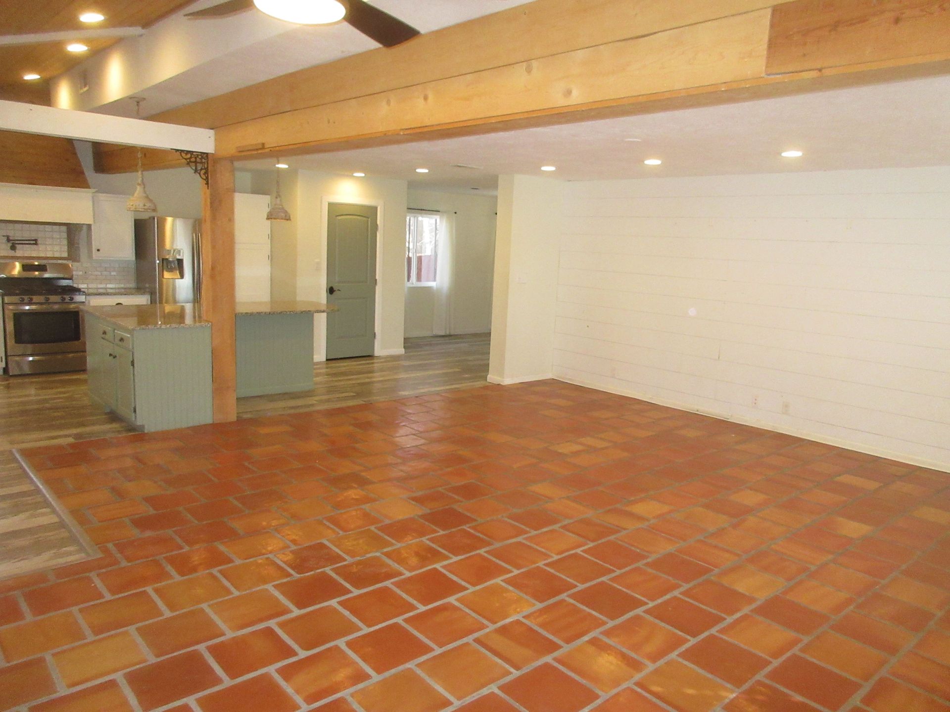 An empty room with a tiled floor and a ceiling fan