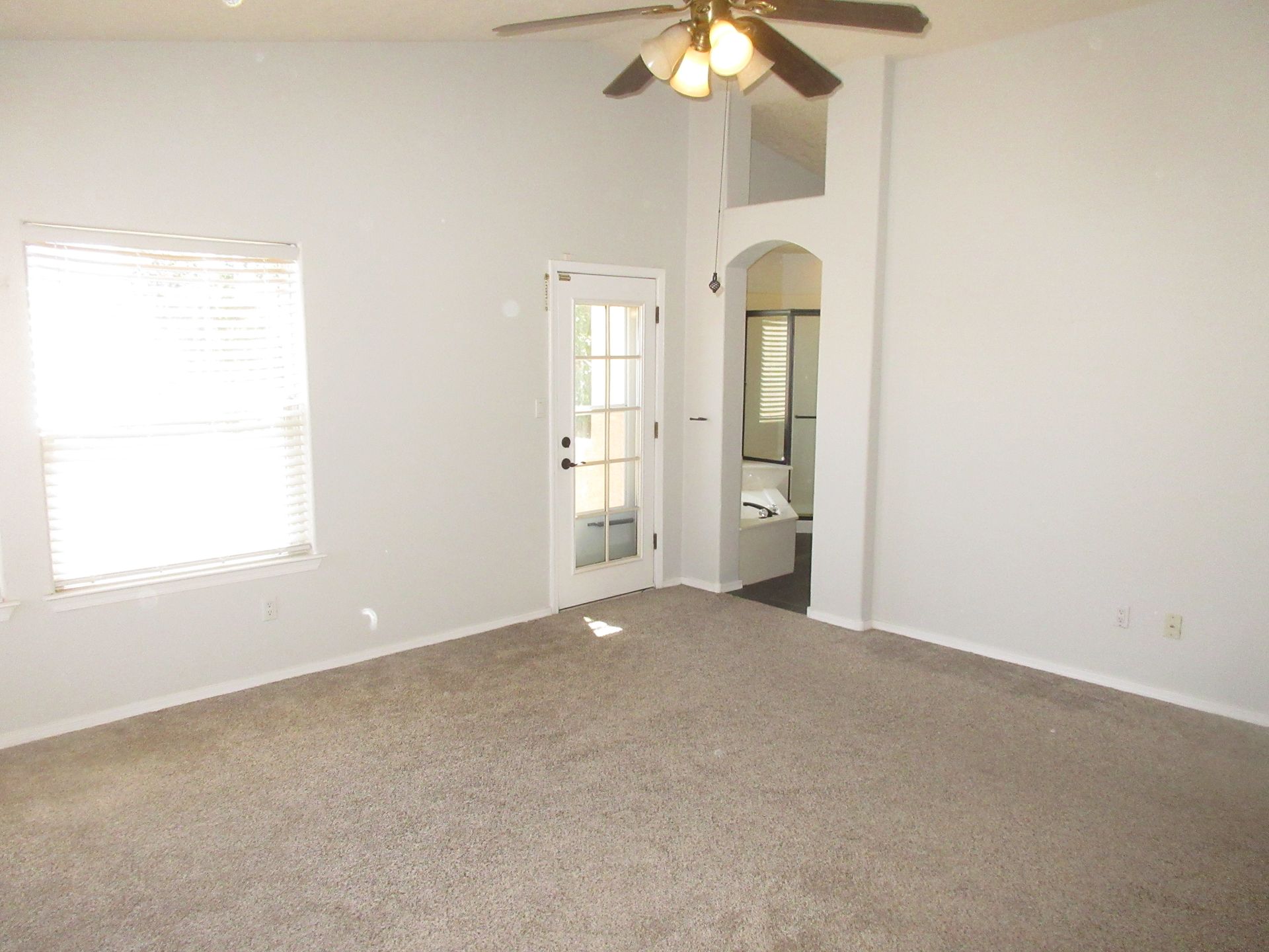 An empty room with a ceiling fan and a window