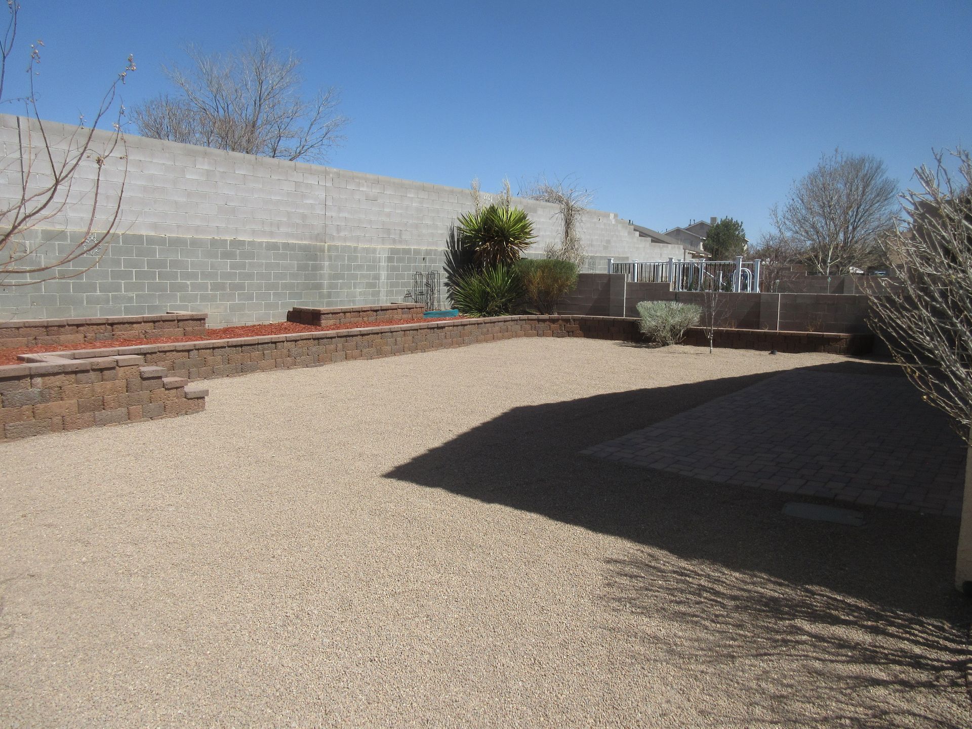 A gravel yard with a brick wall in the background