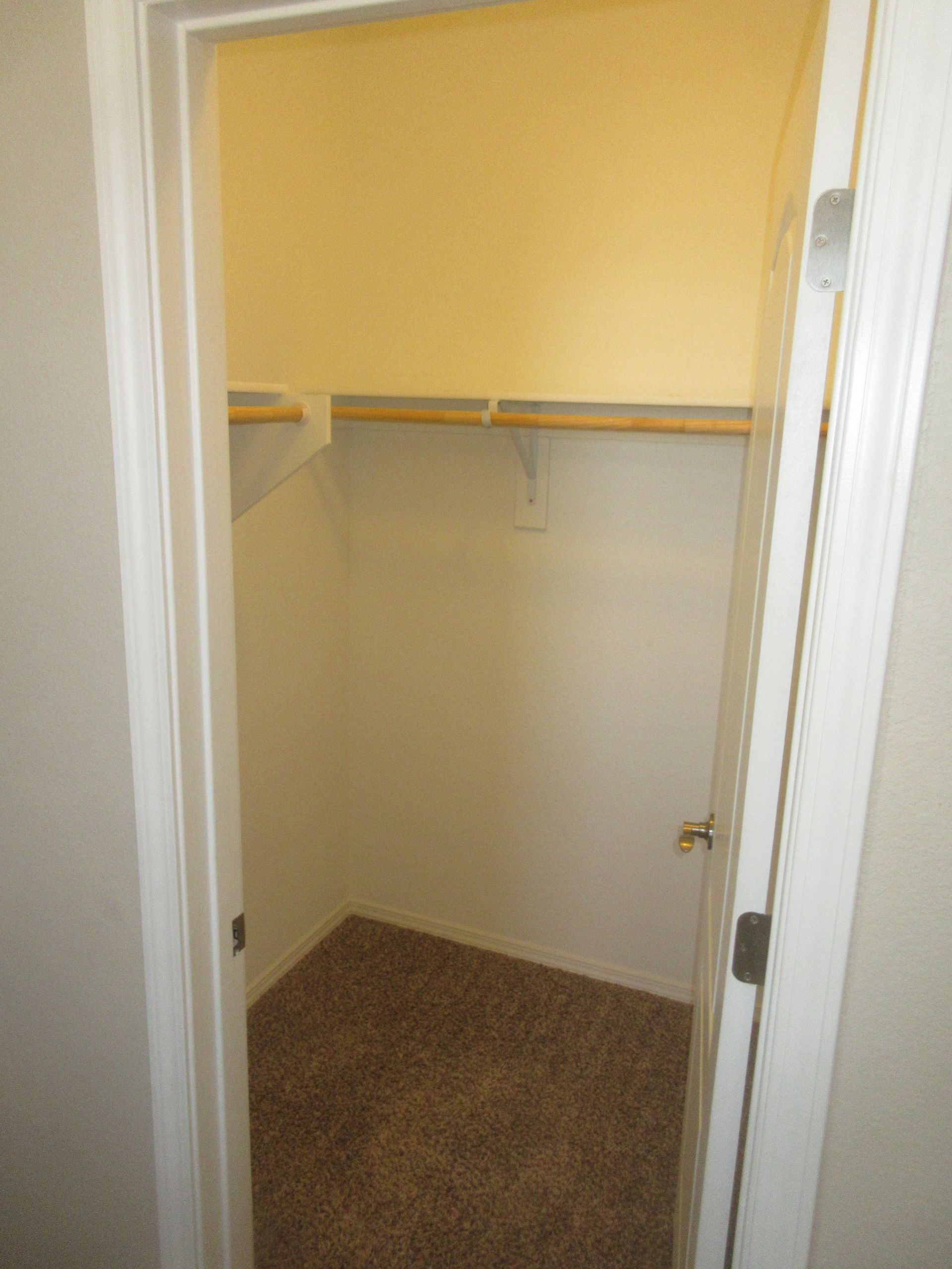 A closet with a door open and a shelf on the wall.