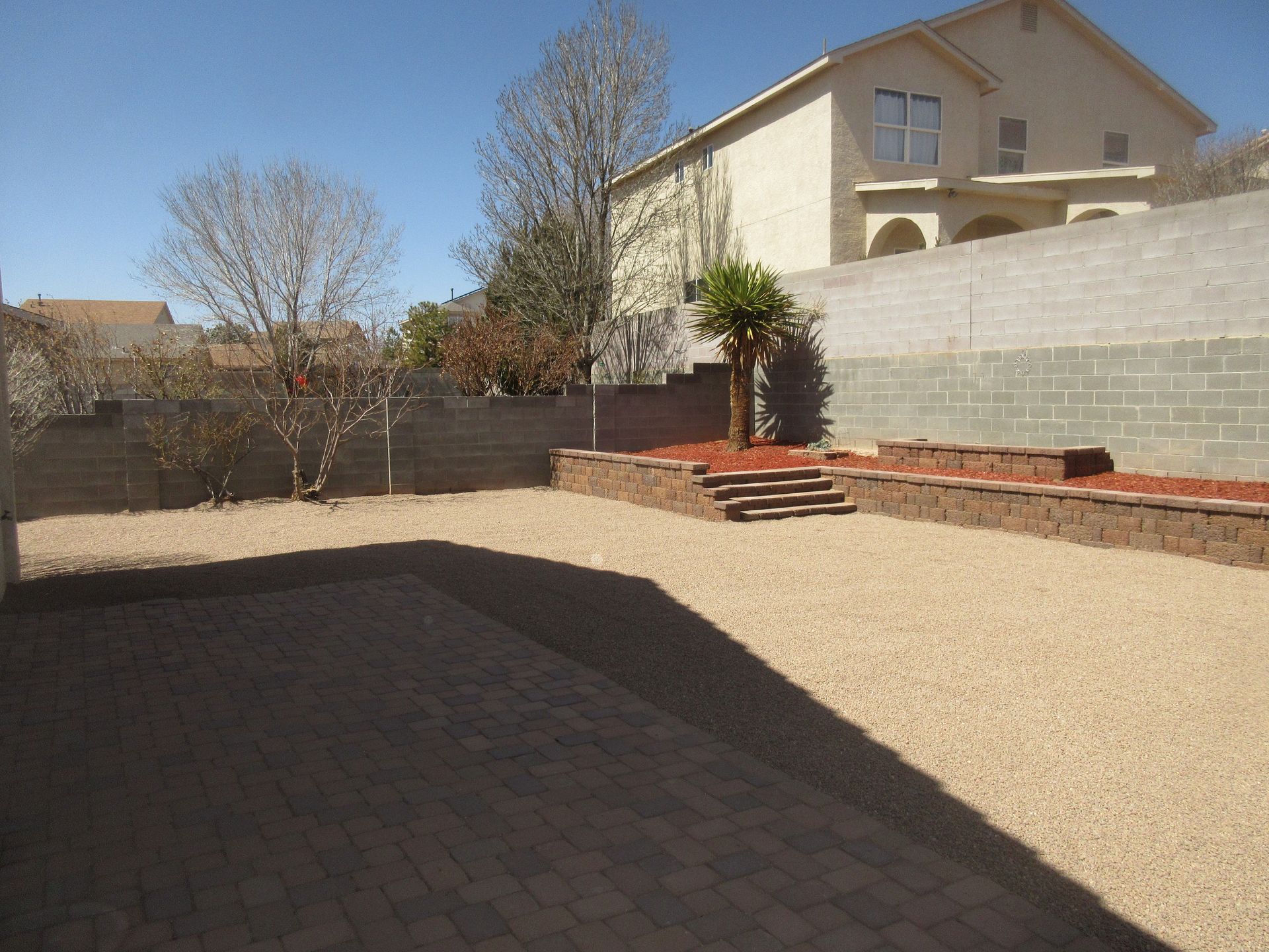 A large house is behind a gravel yard