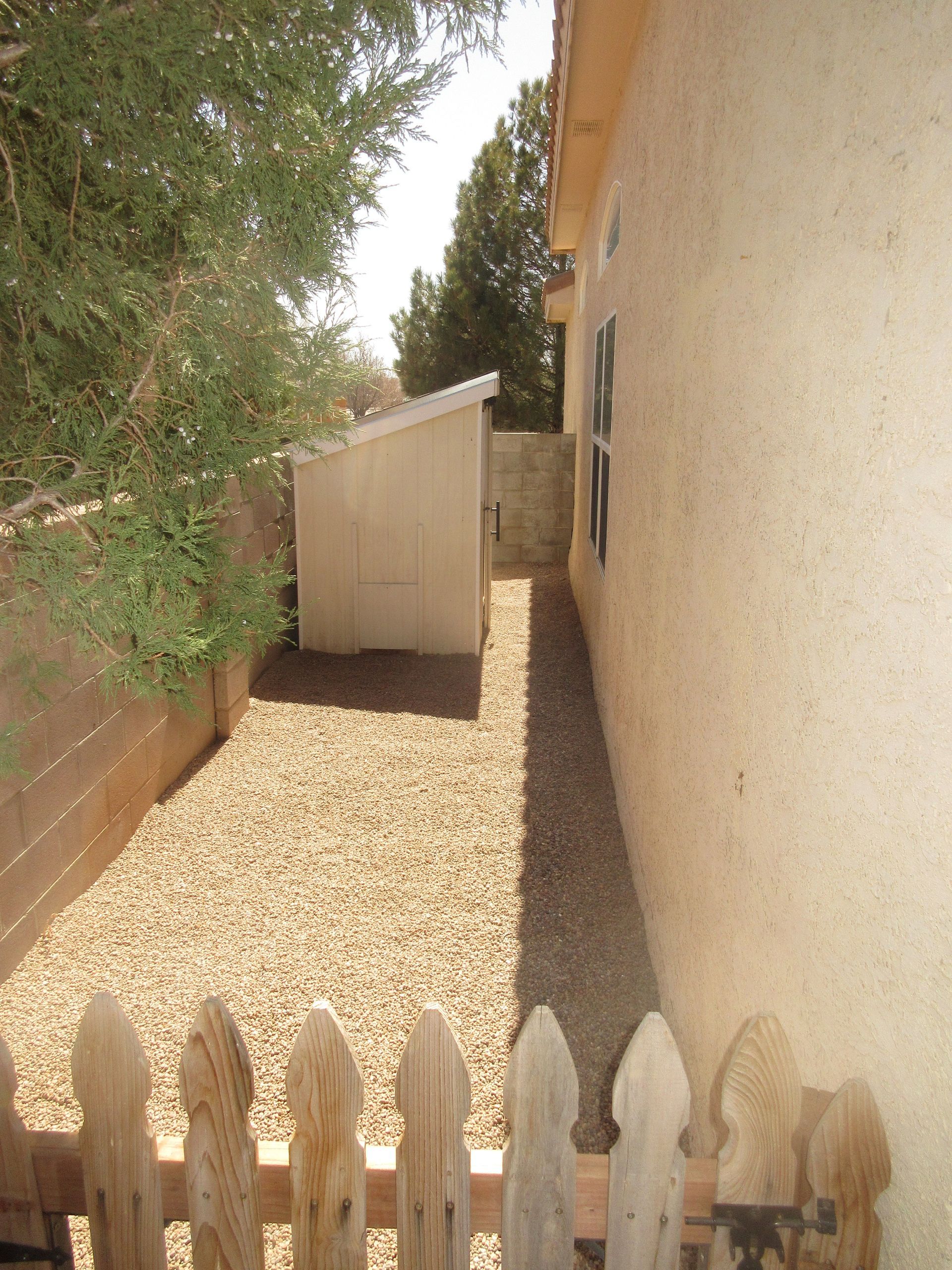A house with a wooden fence and gravel in front of it