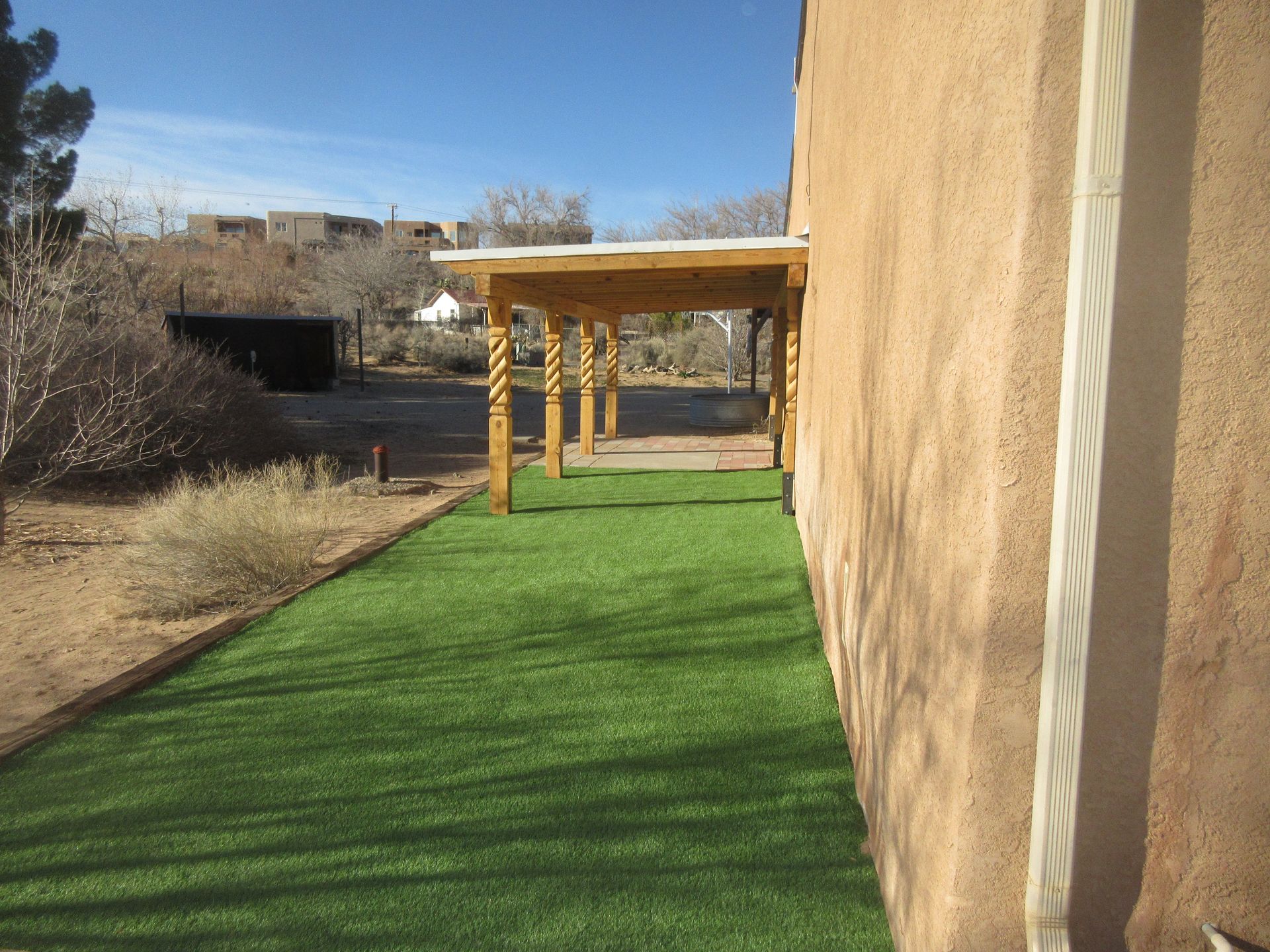 A house with a pergola and a lawn in front of it